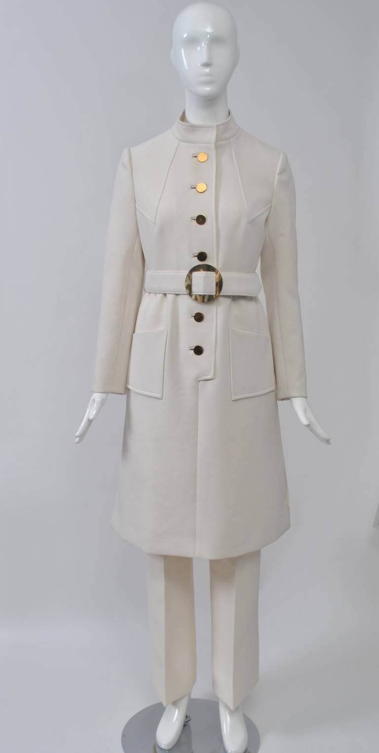 Great detail and design in this dress and pants outfit fashioned of white wool crepe. The modified shirt-style dress sports a mandarin collar and gold buttons in bound buttonholes. Welting detail outlines the diagonal Vs on the bodice and trims the