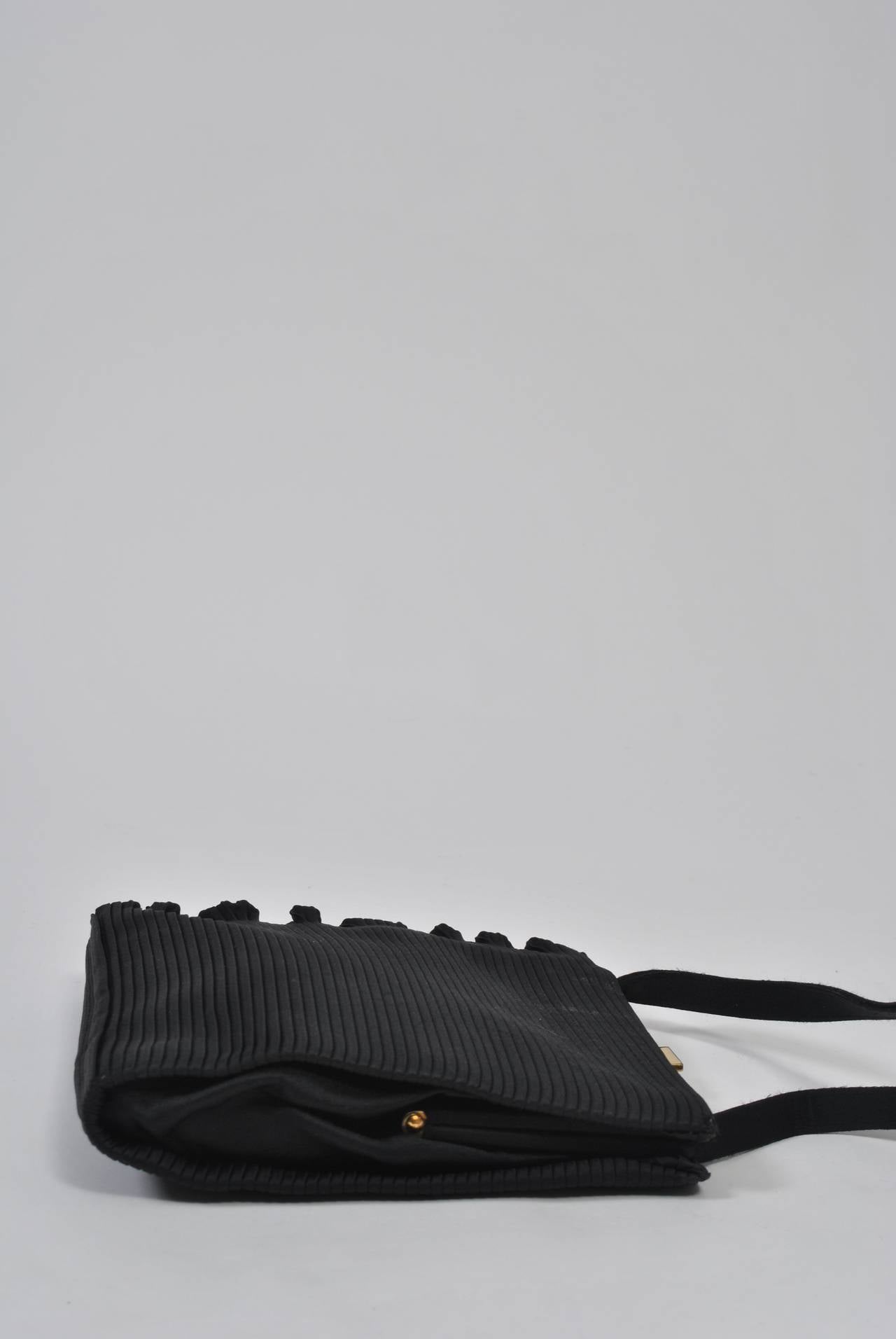 Un sac du soir inhabituel en satin noir mat à côtes verticales, avec un bord volanté naturel sur un côté. Poignée simple, fermoir en or. Intérieur en satin noir avec compartiment latéral. Discret et élégant. Pas d'étiquette.