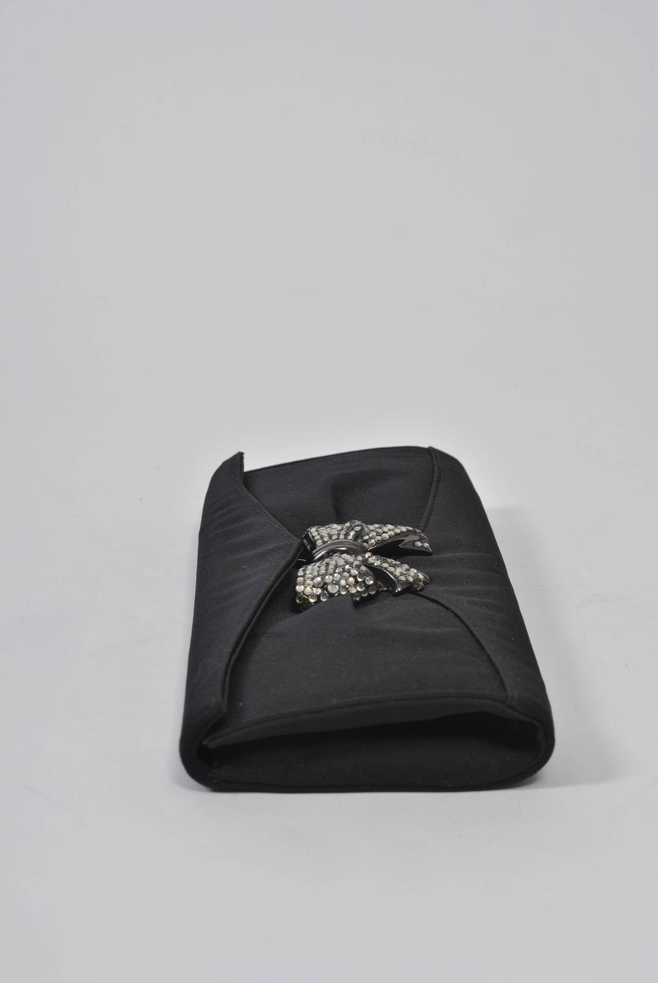 Perfect evening clutch by Rodo, rectangular in shape and featuring a marcasite rhinestone bow clasp. Interior has zippered compartment and metal chain to convert it to a shoulder bag.