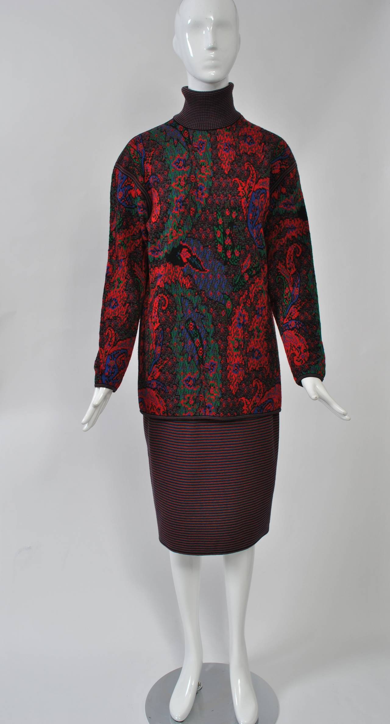 Ungaro two-piece comprising a jacquard wool knit turtleneck in predominantly red and black with blue and green accents over a coordinating striped skirt. The long top has dropped shoulders and is bound with the stripe, which also forms the high