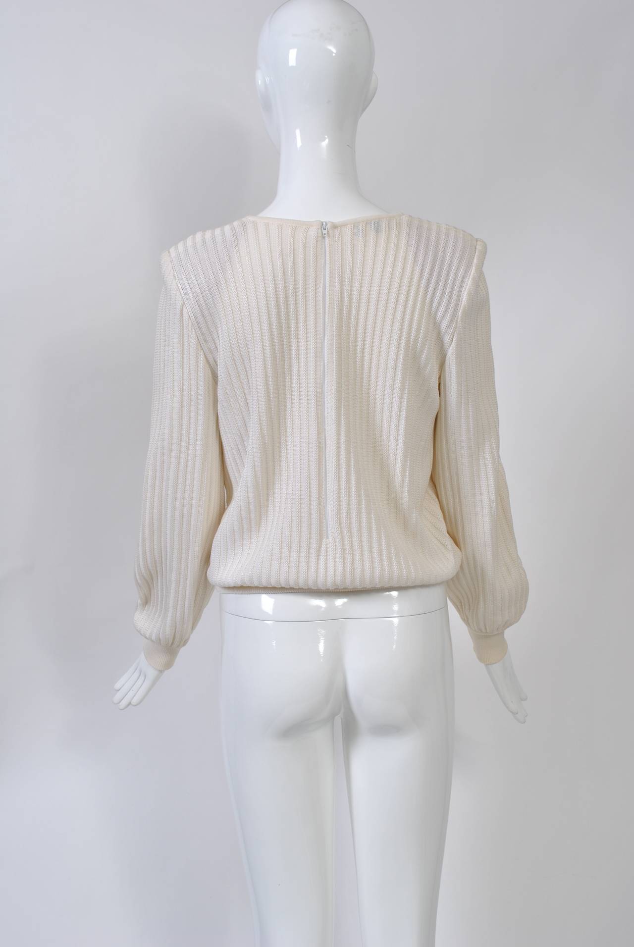 Valentino pullover in white ribbed wool knit with a triple flower design at top right. The perforated flowers are adorned with rhinestones. Flat knit cuffs and hip band. Back zipper.