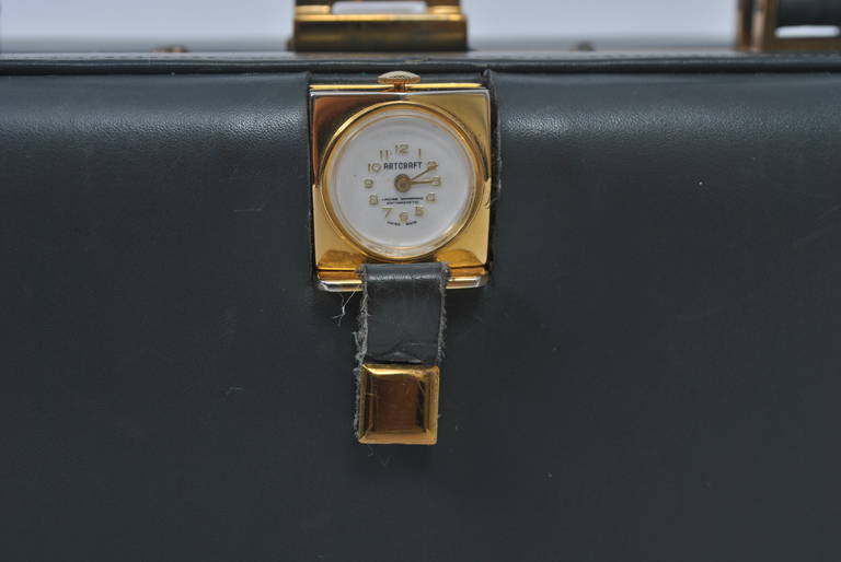 1960s box bag in gray leather with integral watch and gold tone hardware frame surround. Interior with side compartments. Watch in working order.