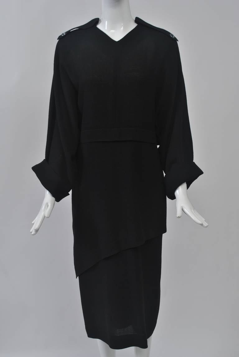 Simplicity coupled with great detailing defines the work of Jean Muir. This dress is typical of her aesthetic while reflecting the designs of the 1980s. It features a loose fit with a shallow V neck, epaulettes with black and white buttons, and an