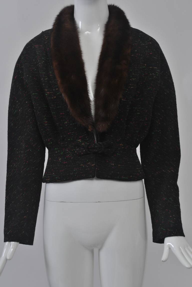 Multi-colored tweed on black wool jacket featuring a fitted waist, peplum that forms blouson in back, and a shawl collar in mink. That raglan sleeves are tapered at the wrist. Hook closure at waist with knot detail.