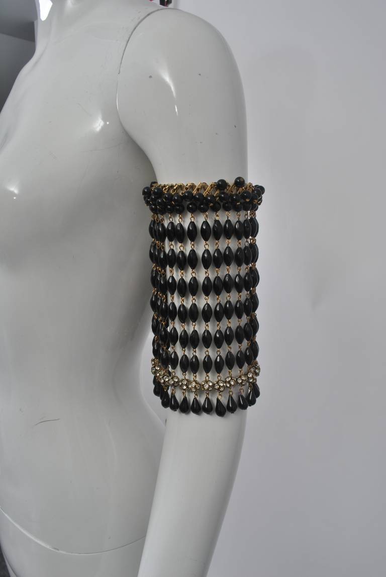 Make an entrance with this unusual and eye-catching arm band composed of long rows of black beads with rhinestone rondels at bottom and expandable cuff at top. Perfect accessory for that ubiquitous LBD and holiday partying/entertaining.