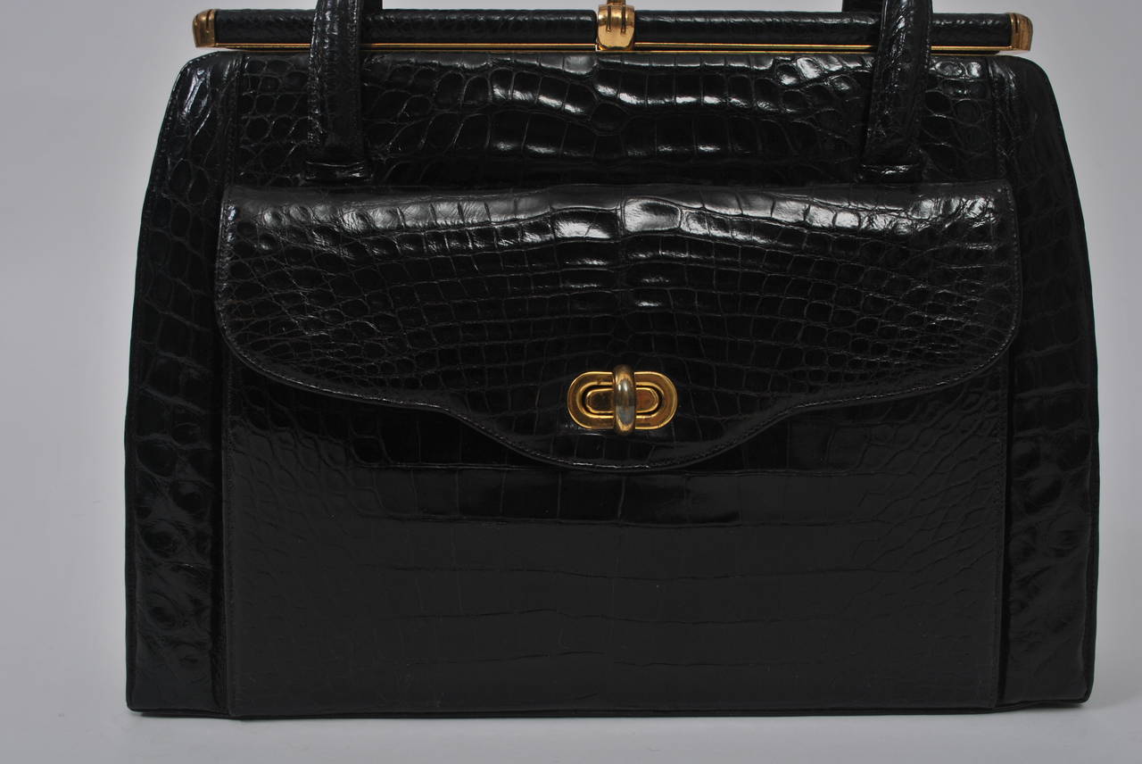 Classic and chic, this large handbag in black alligator features an exterior flap pocket and double handles, as well as a roomy, fitted interior with multiple compartments. Besides its renown as a beauty emporium, Elizabeth Arden  retailed high-end