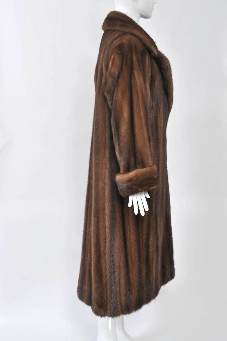Mid-calf length mink coat in medium brown, simple straight styling with notched collar and roll-back cuffs. Dropped shoulders with padding. Full, luxurious skins with nice markings. Fur hook closures, slit pockets. Full cut, approximate size 8-10.