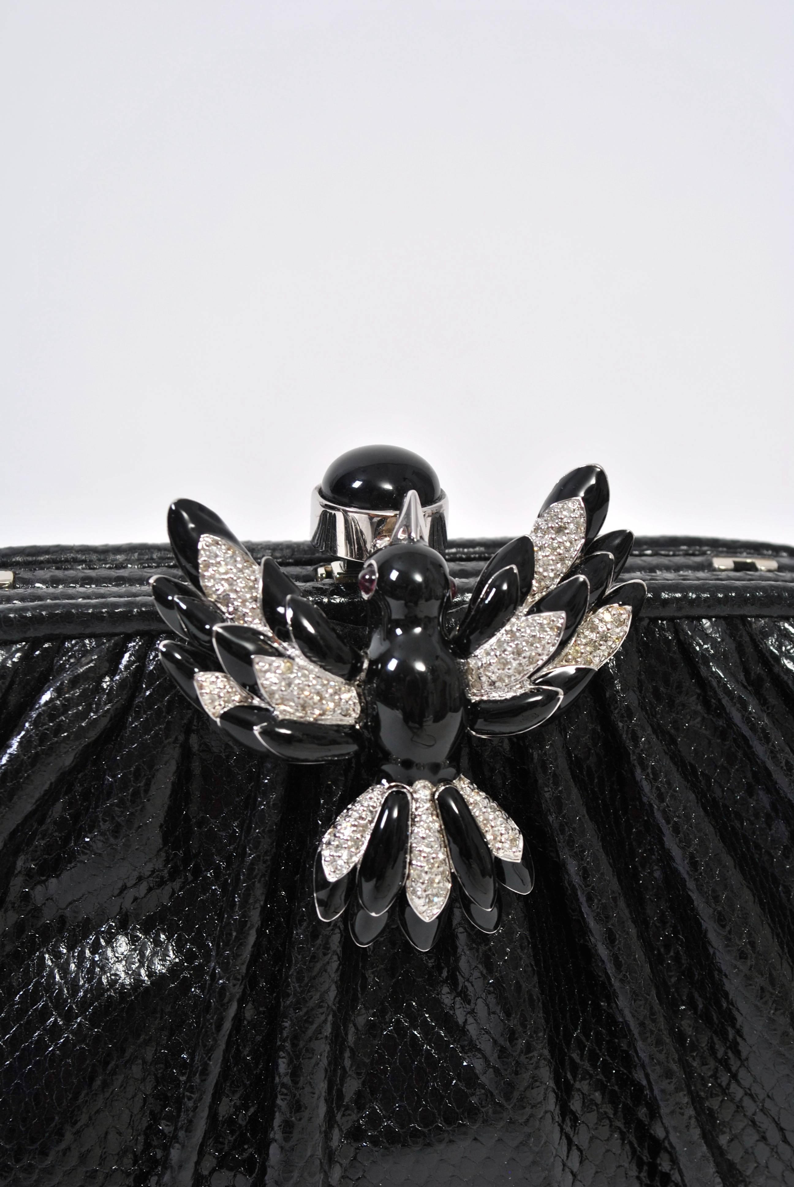 Black karung clutch by Judith Leiber perfectly embellished with a black enamel and rhinestone bird clasp. Converts to shoulder bag with narrow strap that conceals within. Nice interior with signature comb, mirror and change purse. 
