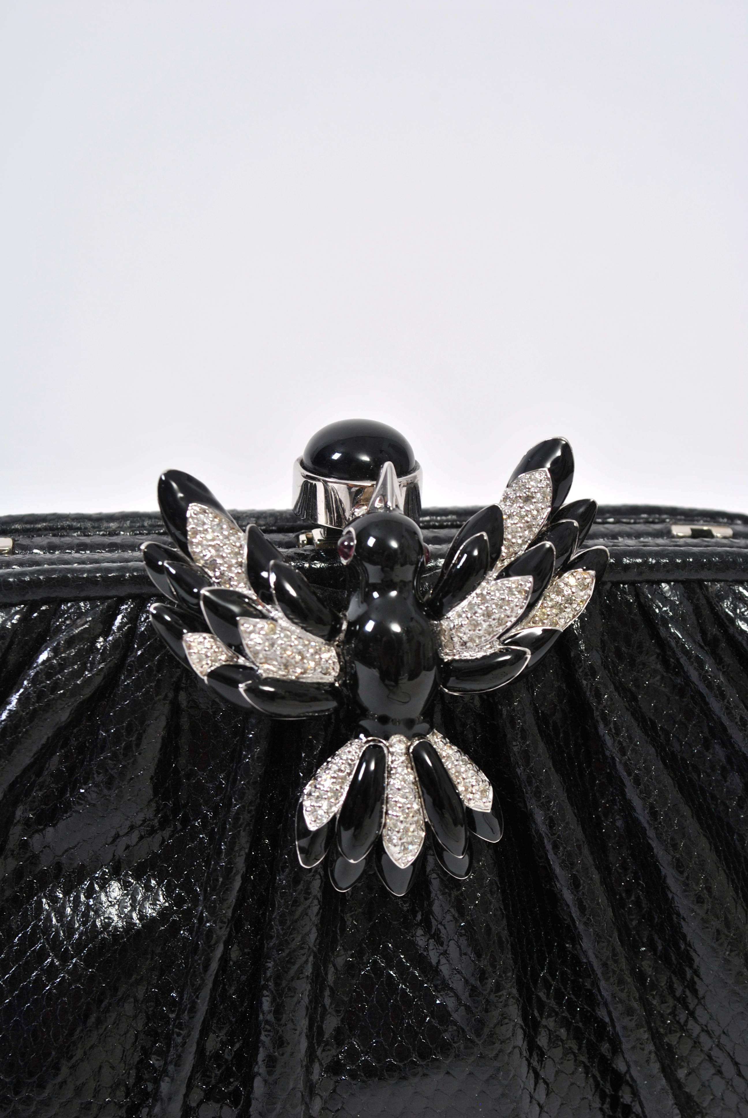 Pochette in karung nero di Judith Leiber perfettamente impreziosita da una chiusura a uccello in smalto nero e strass. Si trasforma in borsa a tracolla con una cinghia stretta che si nasconde all'interno. Interni di pregio con pettine per la firma,