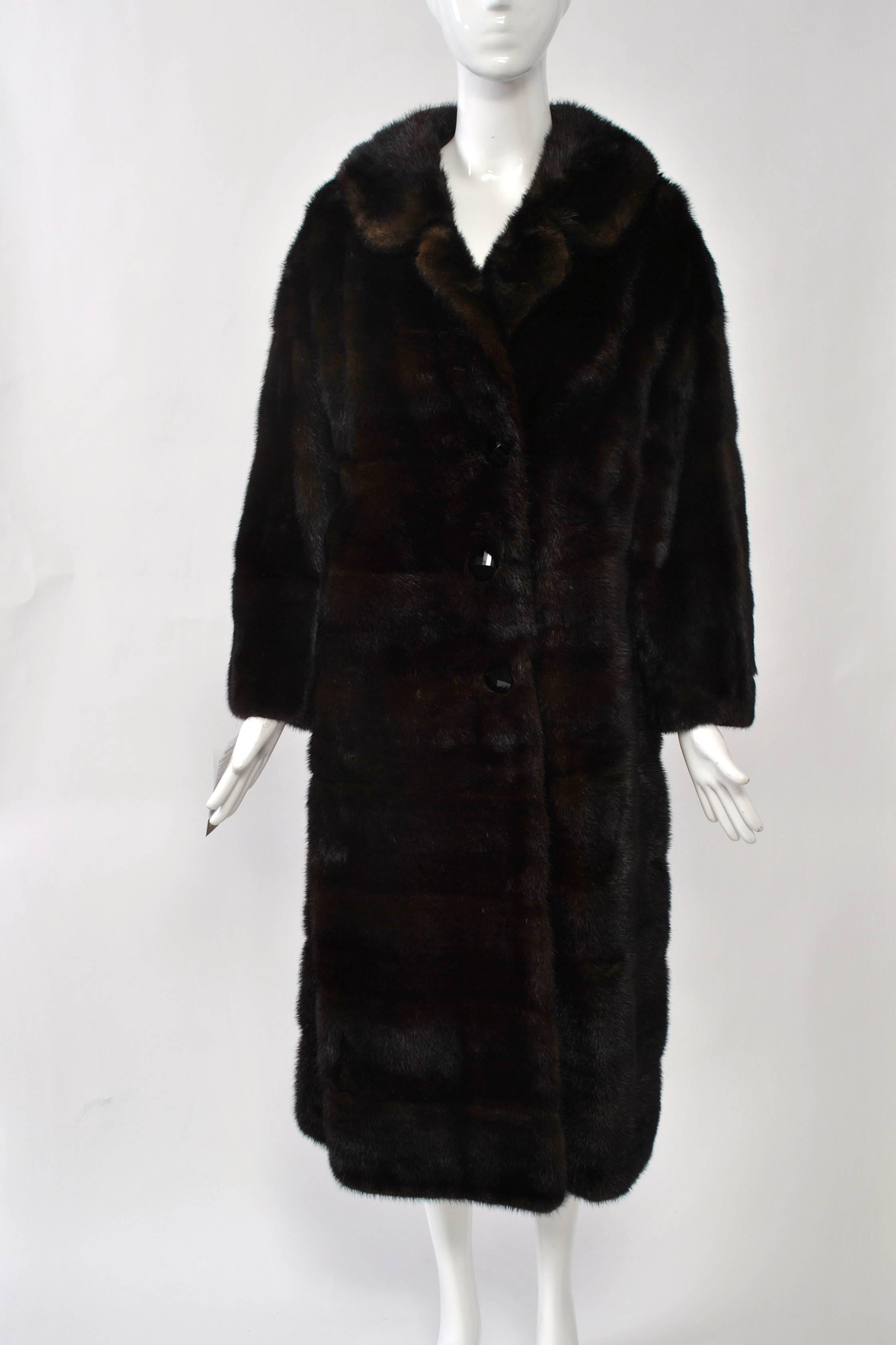 1960s-'70s mahogany mink coat with horizontal skins. Single breasted with spread collar that can be buttoned closed for warmth. Silk lining with pleated hem and velvet trim.