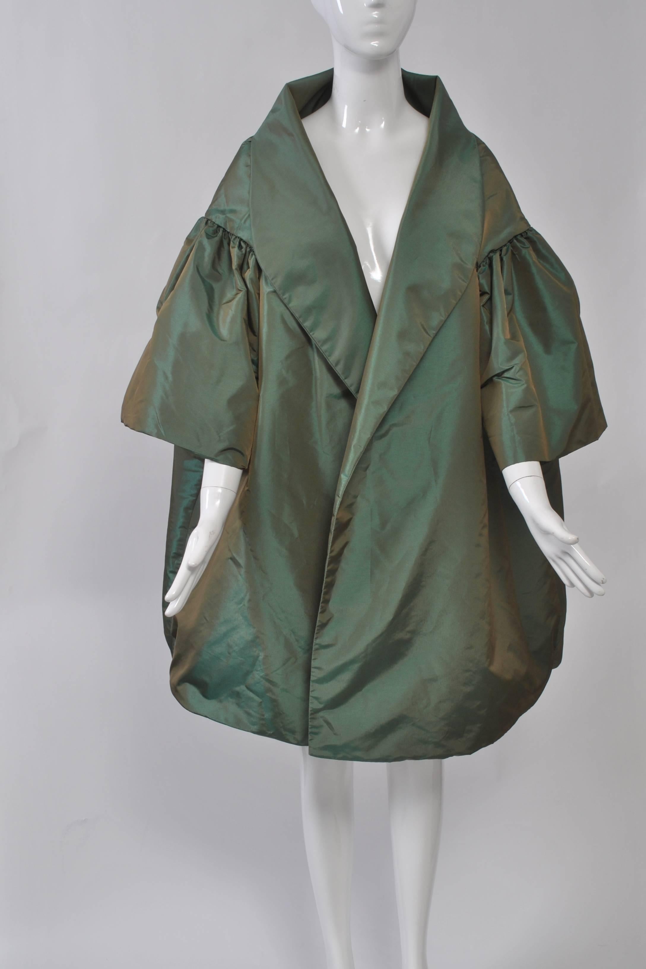 Dramatic evening coat in iridescent blue/green taffeta with oversized cocoon styling, featuring a shawl collar, dropped shoulders with shirred short sleeves, and deep yolk. 