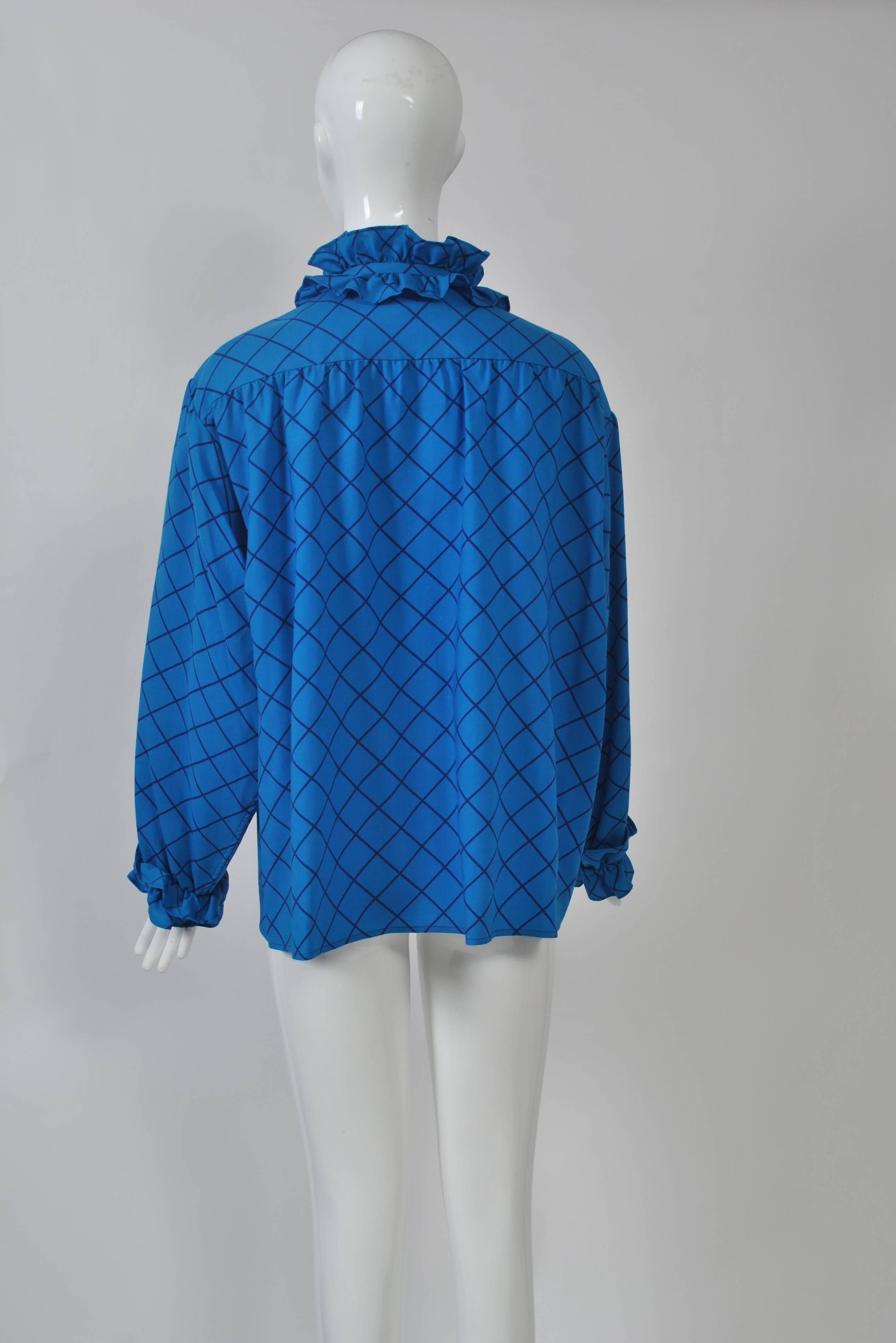 1980s bright blue with navy diamond pattern challis blouse by YSL Rive Gauche features ruffle front, neck and cuffs and silver buttons down placket front. Full cut with dropped shoulders and shoulder/back yoke.