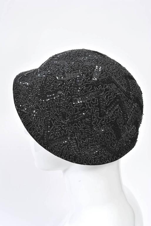 Black felt hat with shallow brim adorned with beads and sequins in a zig-zag and squiggle pattern.