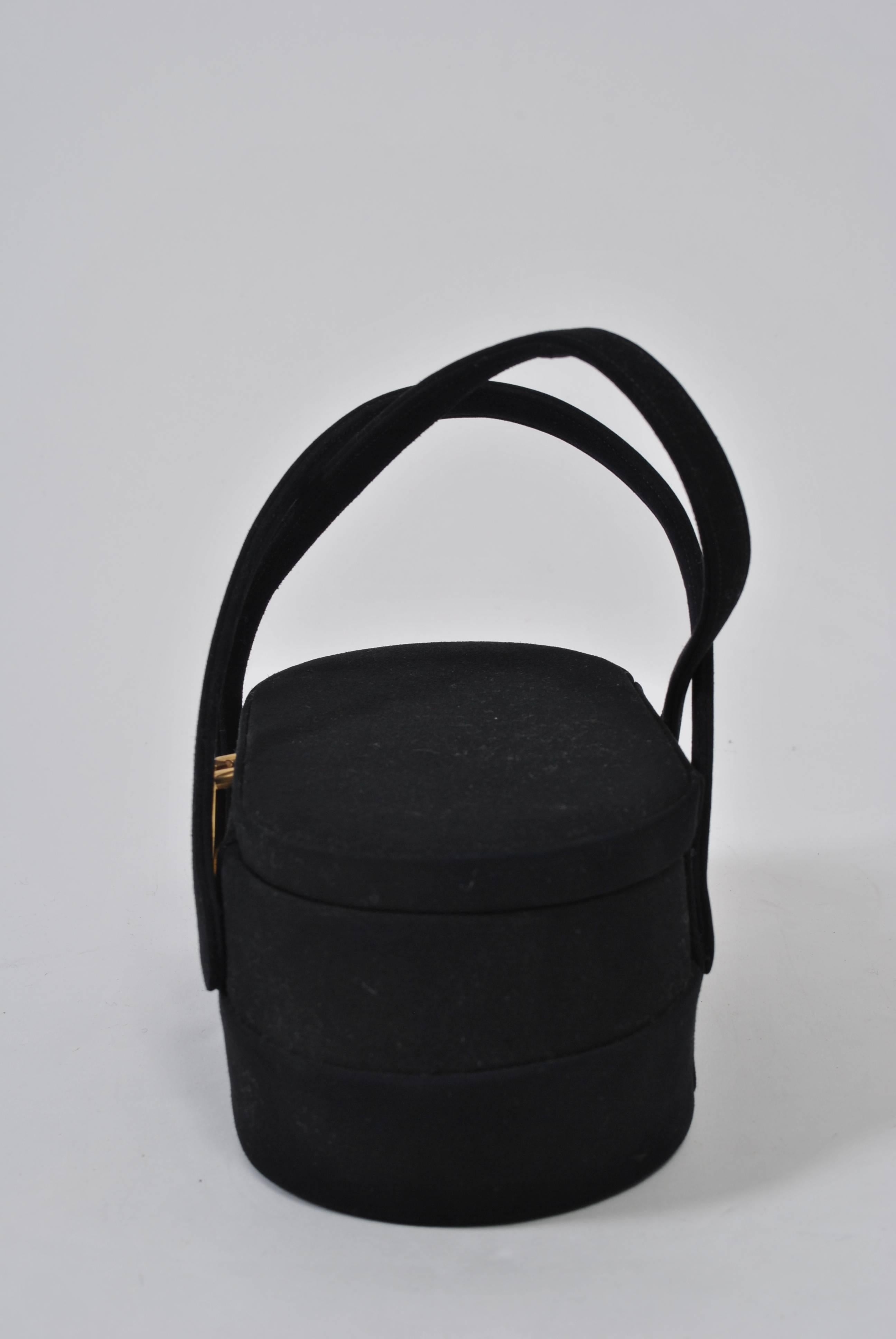 Box-shaped handbags were extremely popular during the 1950s and '60s and their unique styling is evident n this example from Coblentz. In black suede, the bag has an oval shape that is widest at its waist, sports two handles and as its only