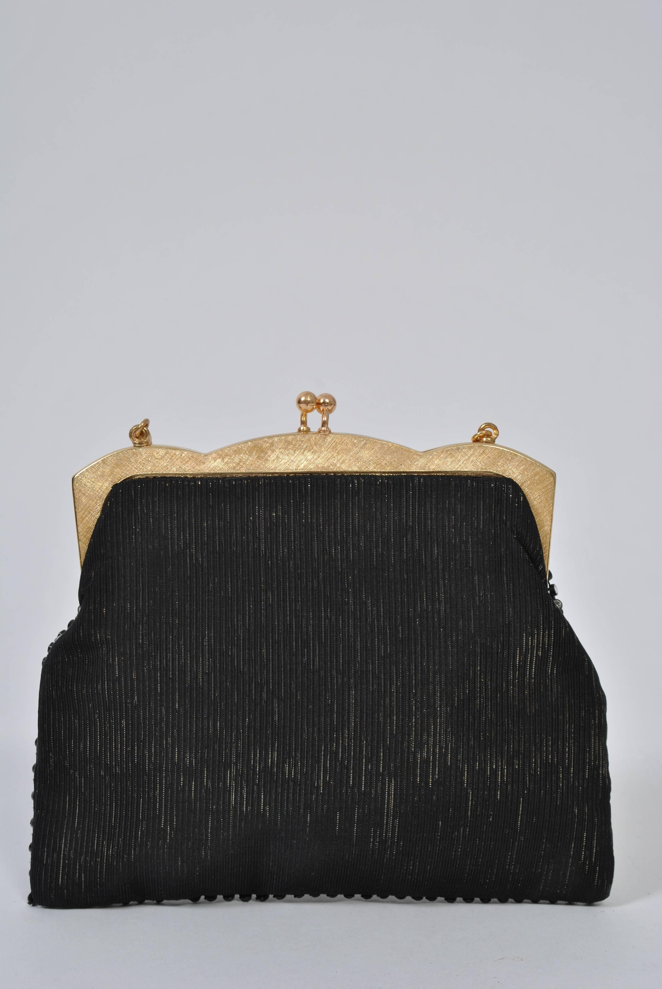 Black evening bag with rhinestones on front, gold frame and chain. Background fabric is gold metallic striated stripe. Black satin interior with side pocket.