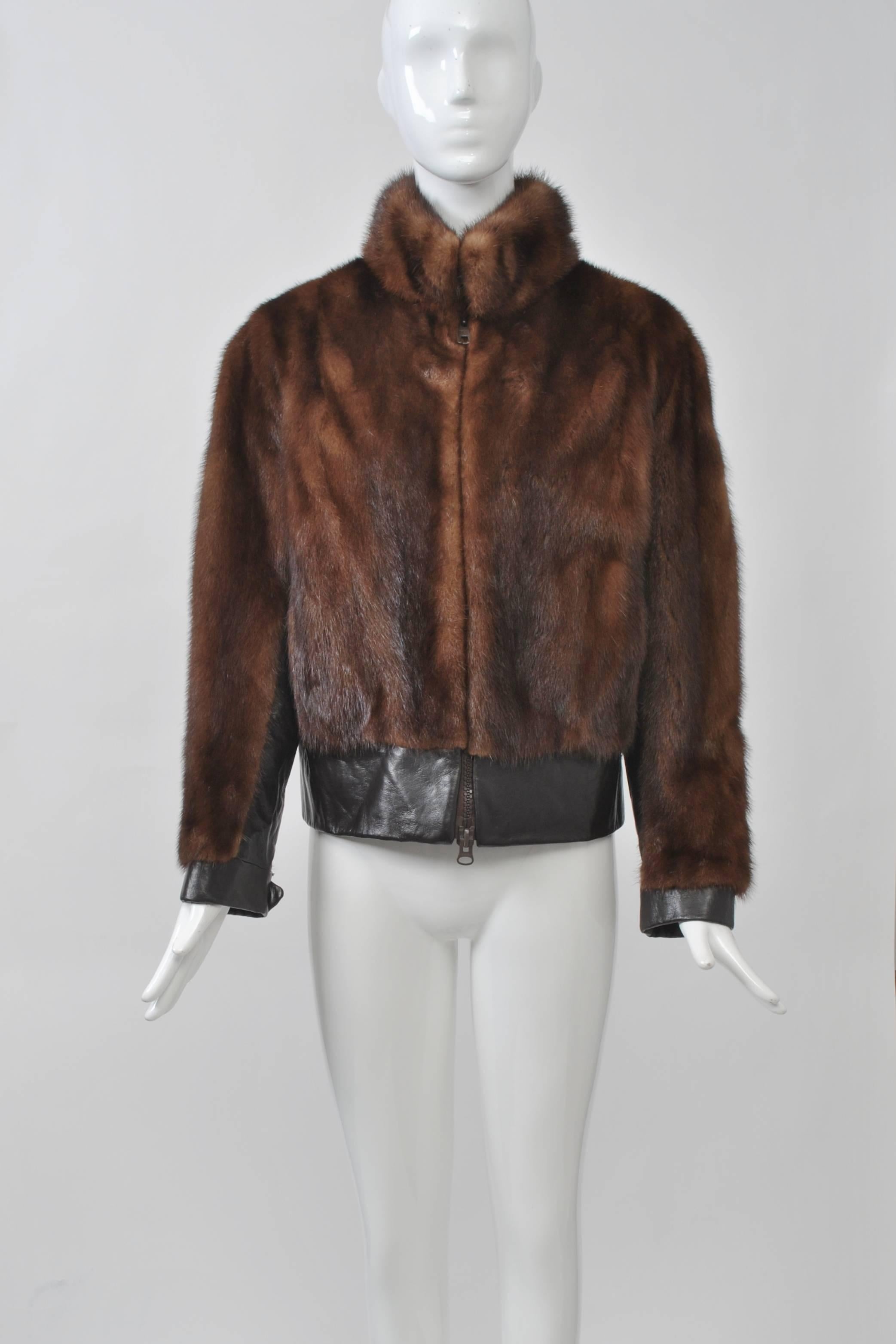 1960s-'70s cropped jacket in brown mink features chocolate leather trim around waist, interior sleeves, and buttoned wrists, as well as a front zipper and stand-up collar. Slit pockets. Approximate contemporary size 6-8.