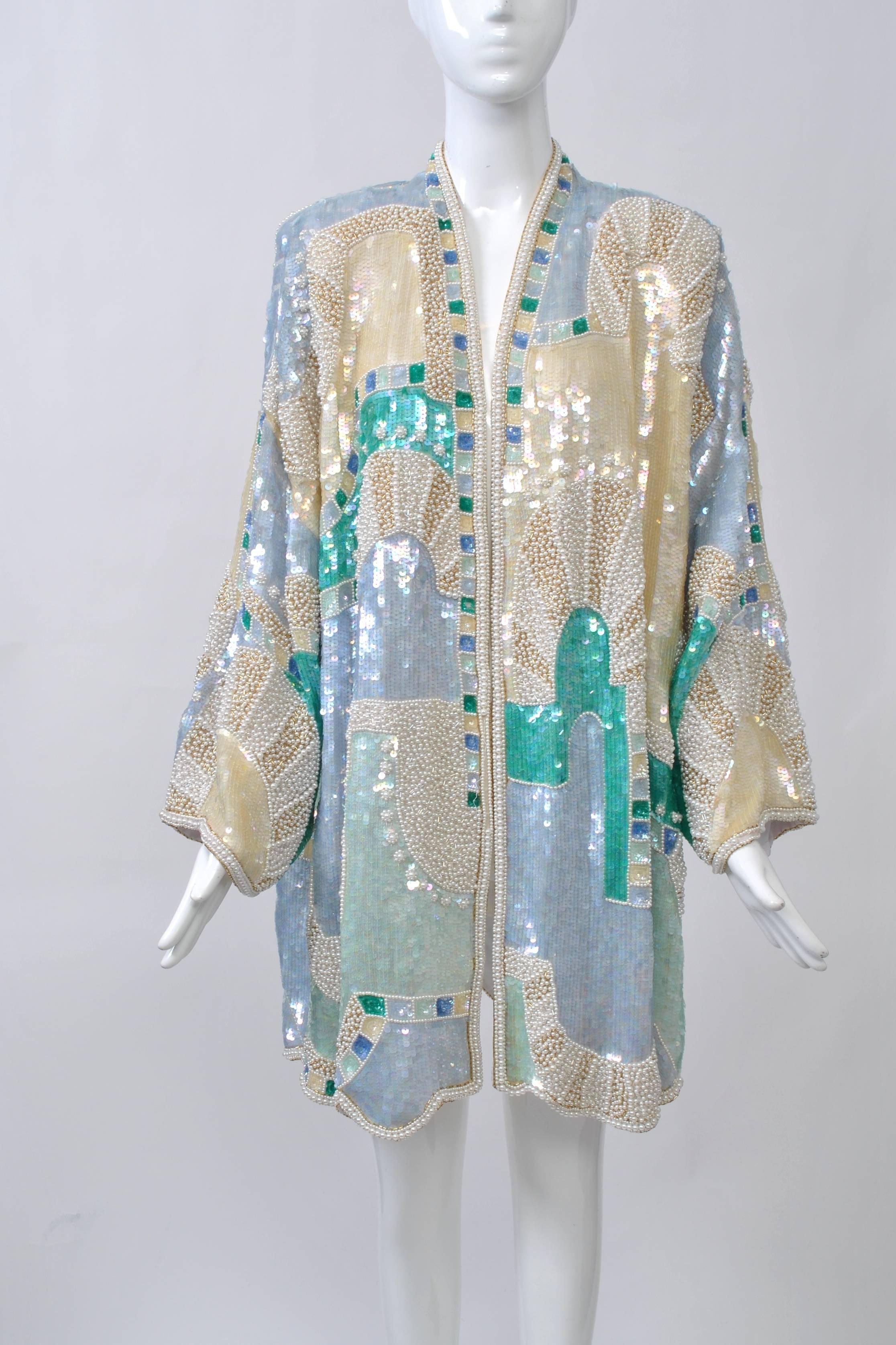 Extravagantly beaded and sequined 1980s 3/4 length coat in blue, ivory, and turquoise hues arranged in an abstract geometric configuration. Open front, wide sleeves, shoulder pads. Retailed by Lillie Rubin, a high-end boutique on New York's 57th St.