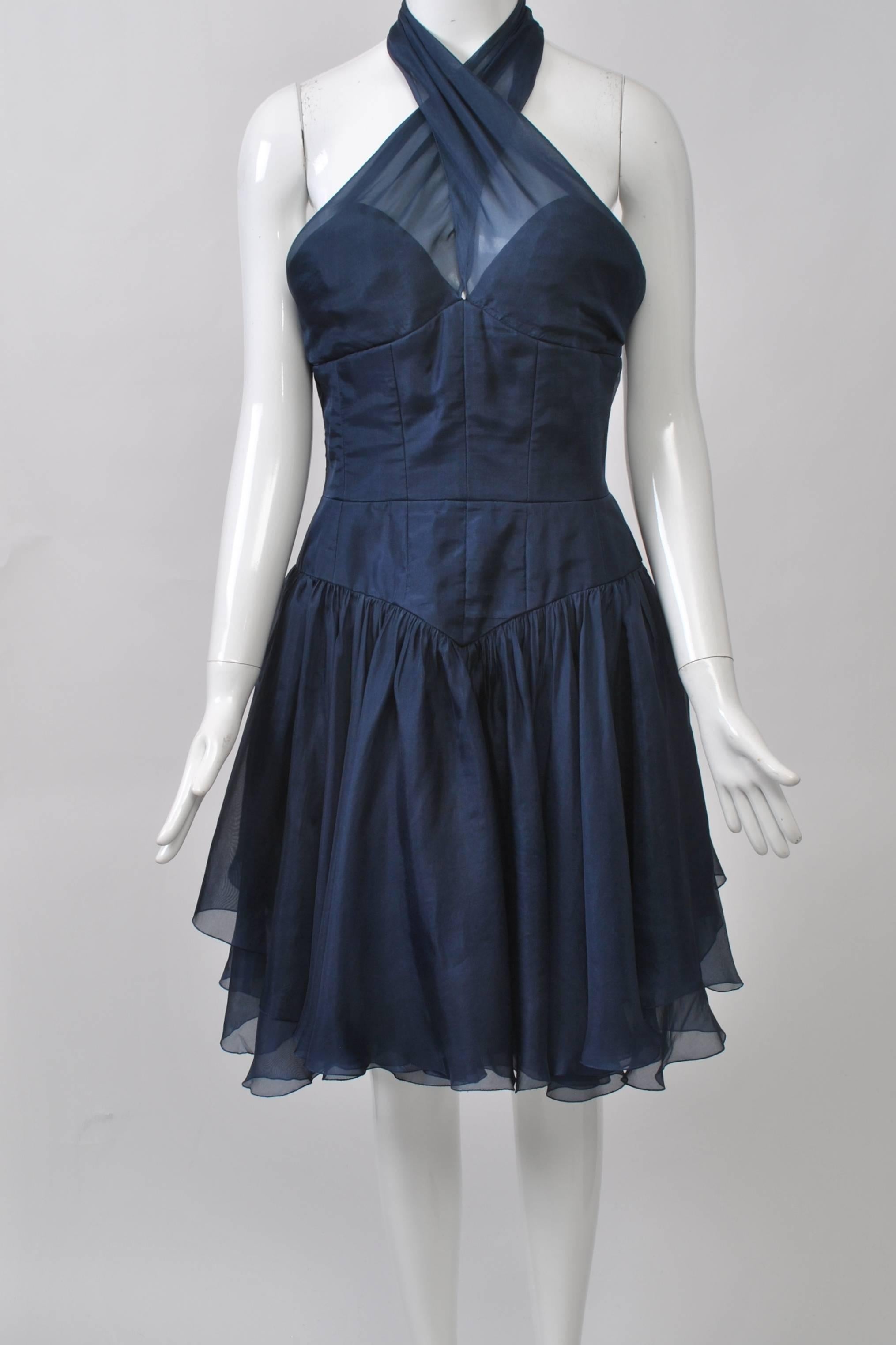 Chanel Boutique navy organza short cocktail dress with criss-cross halter neckline, bustier-style fitted bodice and fitted V-shape hip area. Dropped full skirt composed of several layers of the organza. Halter neck secured by 2 Chanel logo buttons.