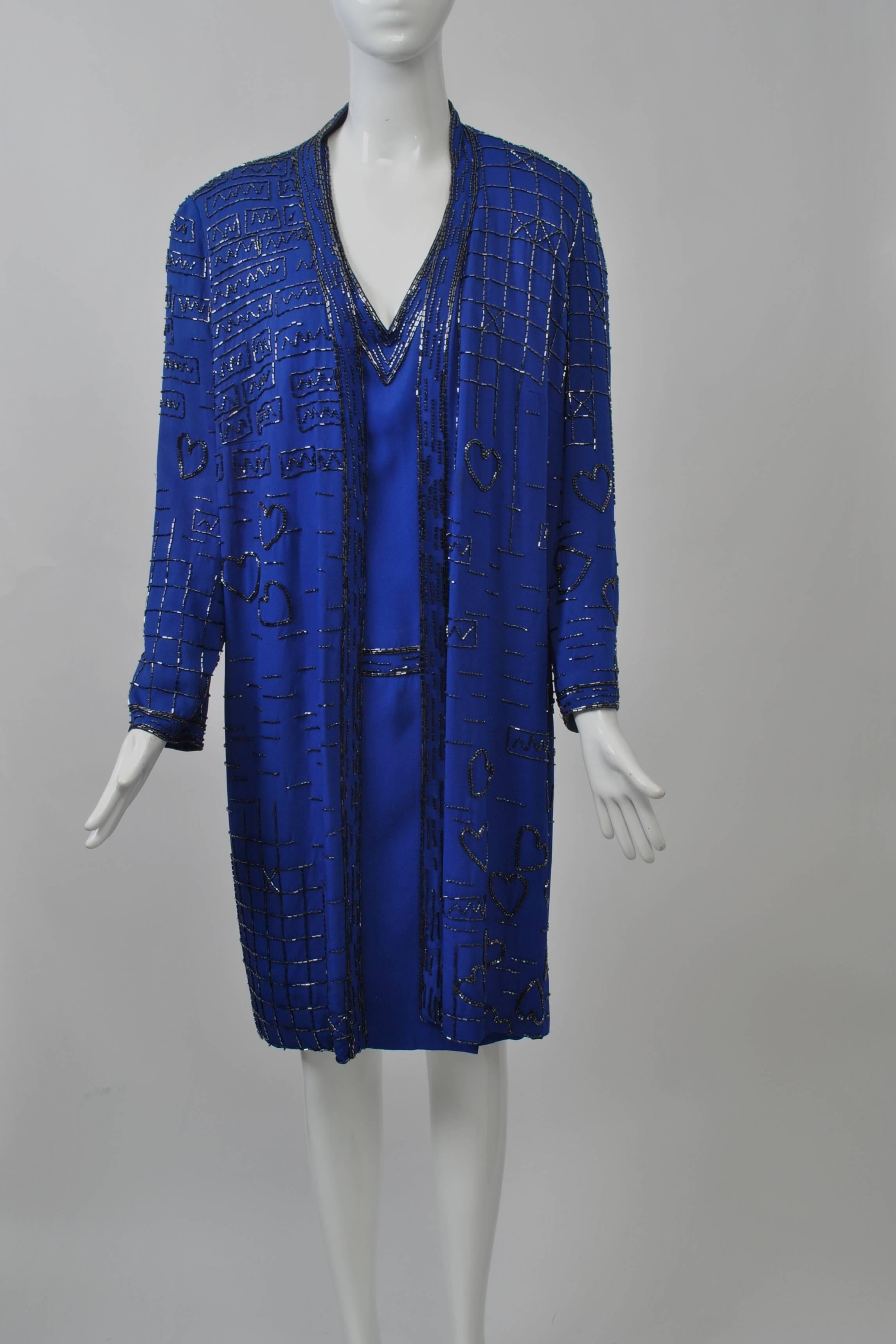 1980s royal blue coat and dress with charcoal beading in geometric patterns and hearts. The open coat reveals a V-neck, 3/4 sleeve dress underneath with straight beading around the neckline, wrists and hipline. Snaps down the back. Size M.