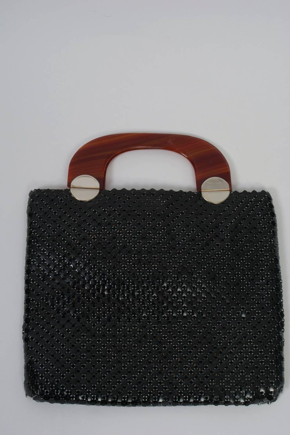 A rare modern design from Whiting & Davis, this 1960s tote ifeatures a large-gauge black mesh and tortoise shell handles with circular gold metal hinges, a motif repeated as a decorative touch on the front of the bag. Interior has side compartment