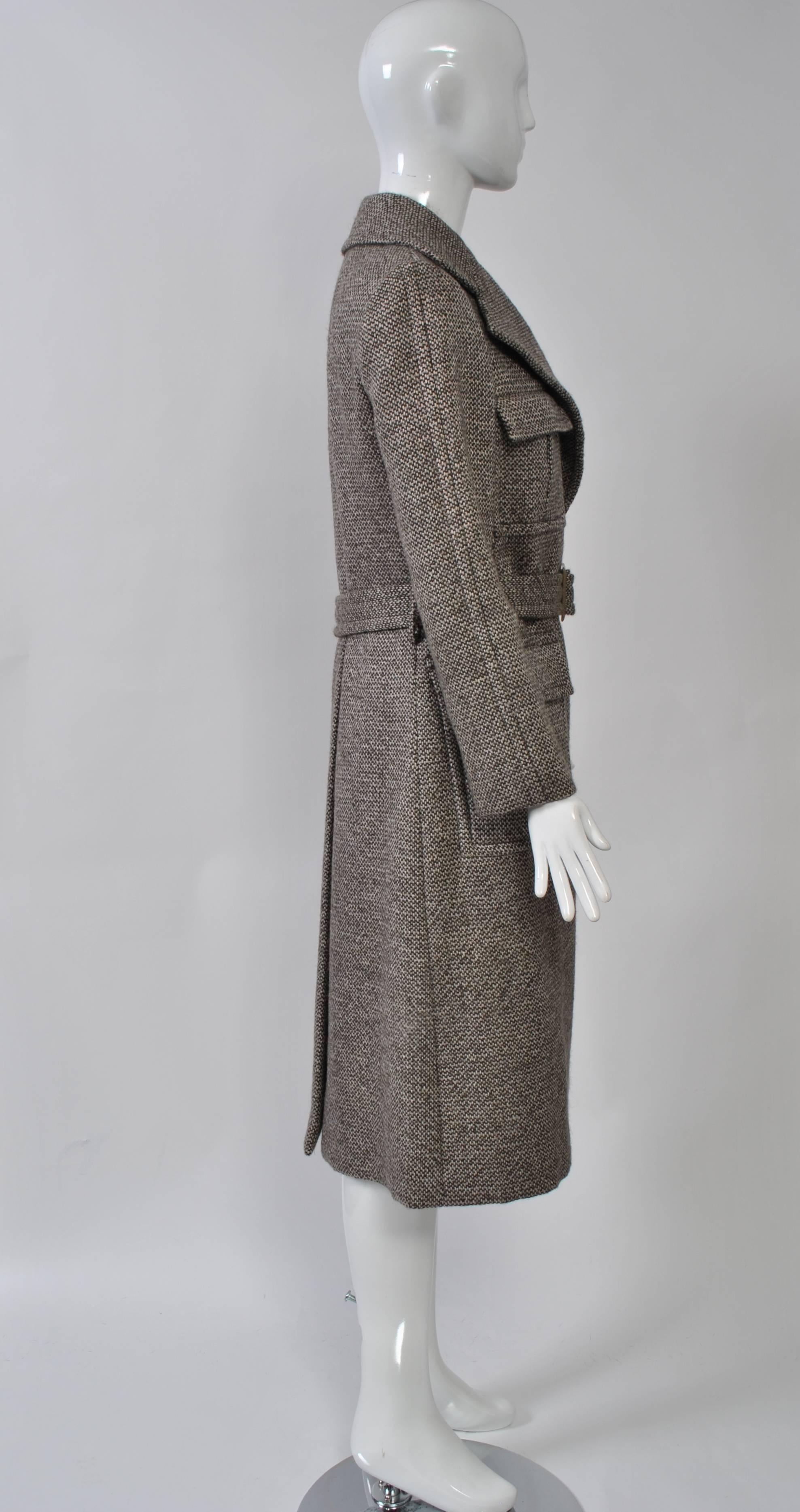 Brown tweed wrap coat by Bill Blass features wide lapels, menswear style patch pockets and a matching tweed belt with buckle. Deep back vent. Brown taffeta lining. Approximate size 6.