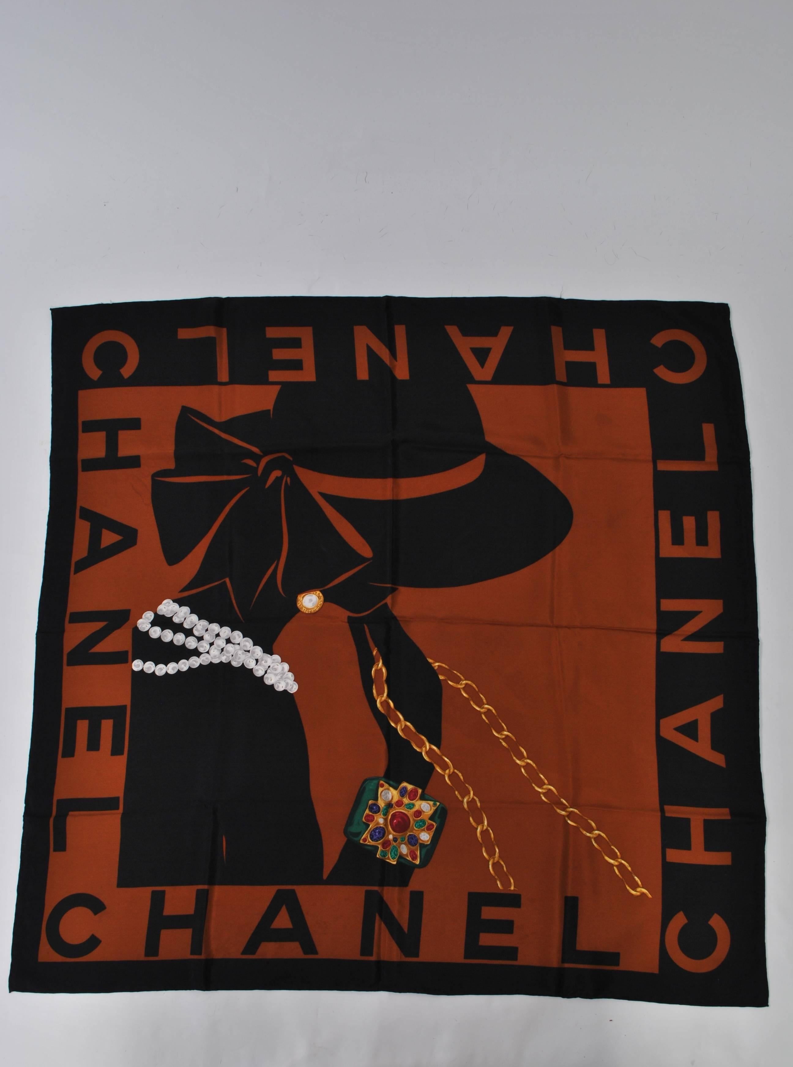 Chanel silk scarf in cocoa and black featuring profile female bust with large hat and classic Chanel motifs - white pearls, leather and metal chain, and multi-stone cross bangle. Looks unused.