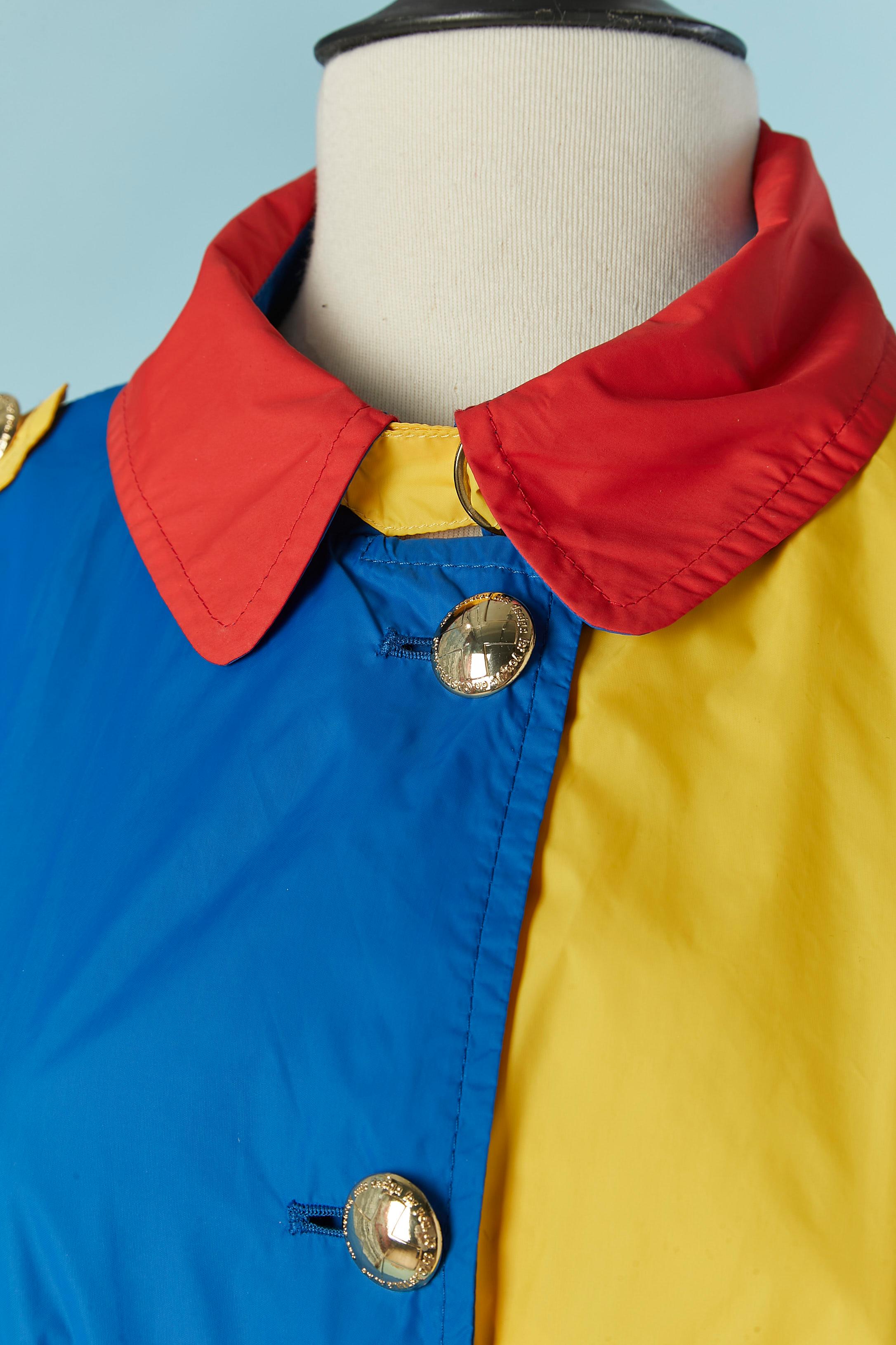 Trench in nylon multicolore. Chiusura con bottone e asola con marchio sul centro della fronte. Chiusura con fibbia sul colletto. Tasca su entrambi i lati + una tasca interna. 
TAGLIA L