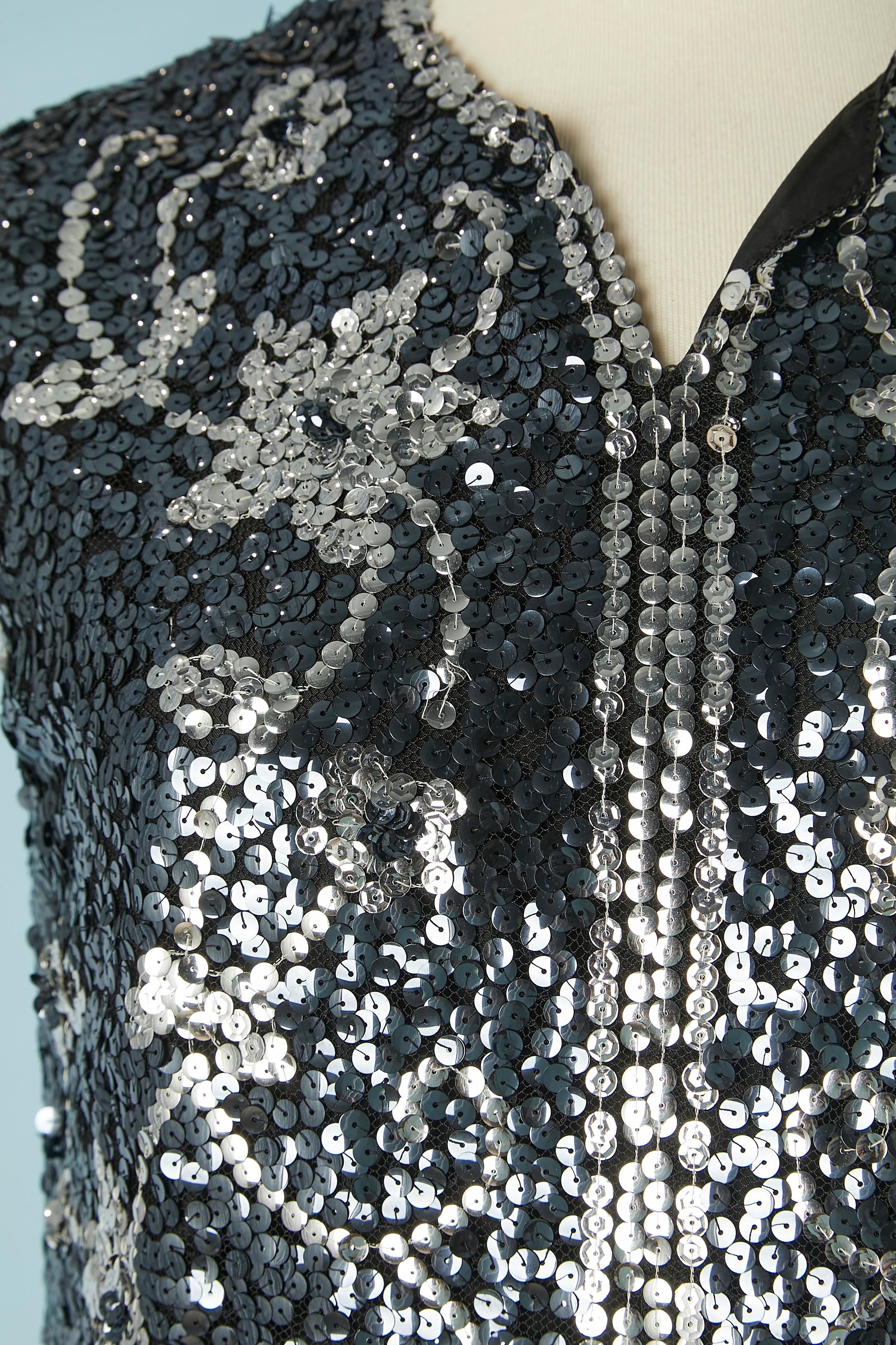 Tunica senza maniche in paillettes argento e nere su una base di tulle. La fodera è probabilmente in acetato o rayon.  Chiusura con zip al centro della schiena. Realizzato a mano in Francia; spaccato sulla parte anteriore centrale.
TAGLIA M 