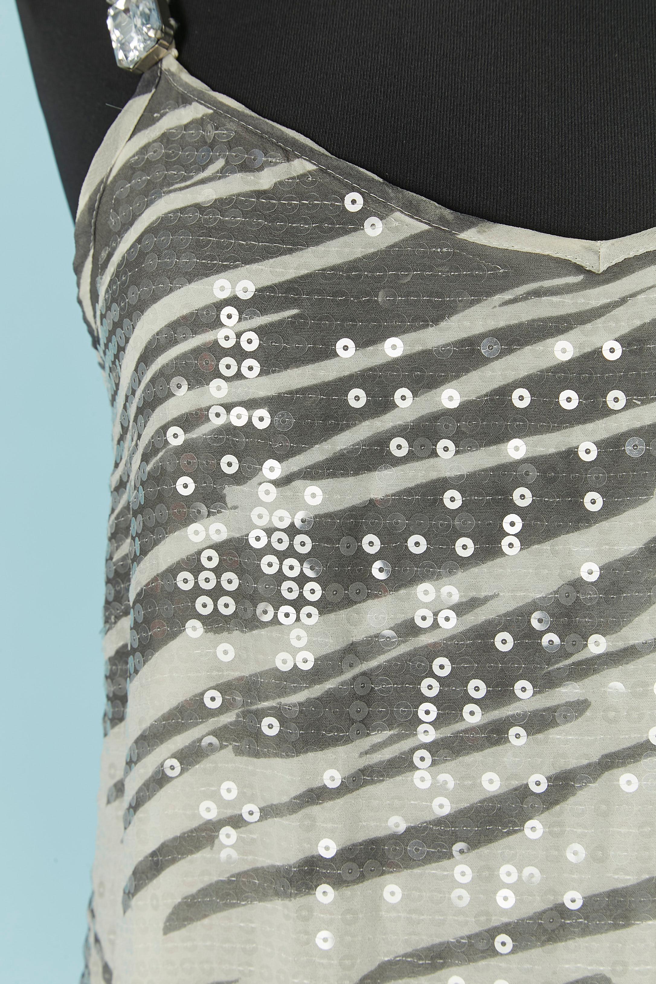 Robe du soir en soie imprimée et paillettes transparentes. Doublure en polyester. 
Fermeture à glissière invisible et crochet sur le côté gauche. Gros strass sur la bandoulière.
Ruban rouge sur le bord inférieur. Bandoulière réglable.
TAILLE M