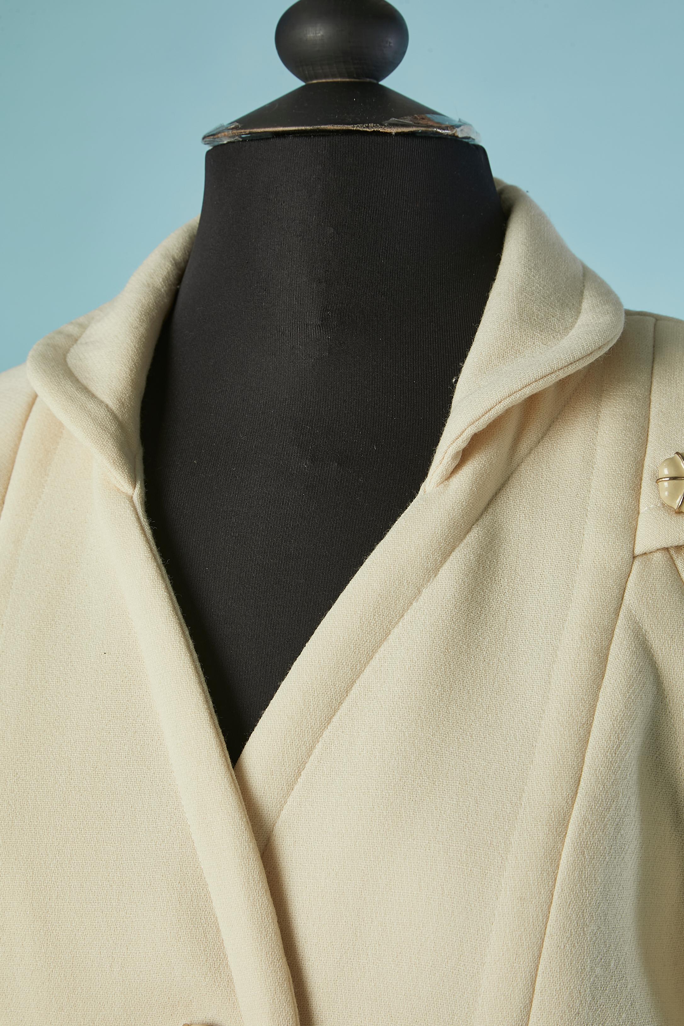 Ivory wool single-breasted jacket with camelia buttons . Silk branded lining. Button and buttonhole closure on the middle front. Raglan sleeve ( only on the front) Shoulder pad. Pocket on both side. Box-pleat on the bottom middle back with button.