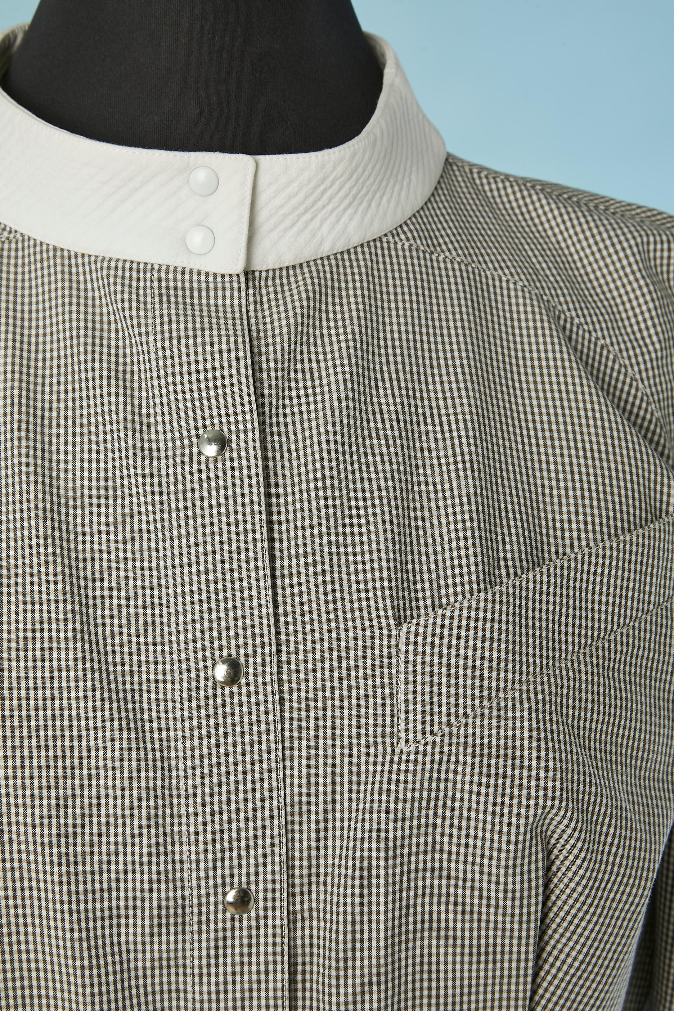 Camicia Vichy bianca e grigia con colletto bianco in piqué di cotone. 
Chiusura a scatto sul centro della parte anteriore. Manica raglan. 
TAGLIA 36 (Fr), ma vestibilità XXS (vita molto piccola) 