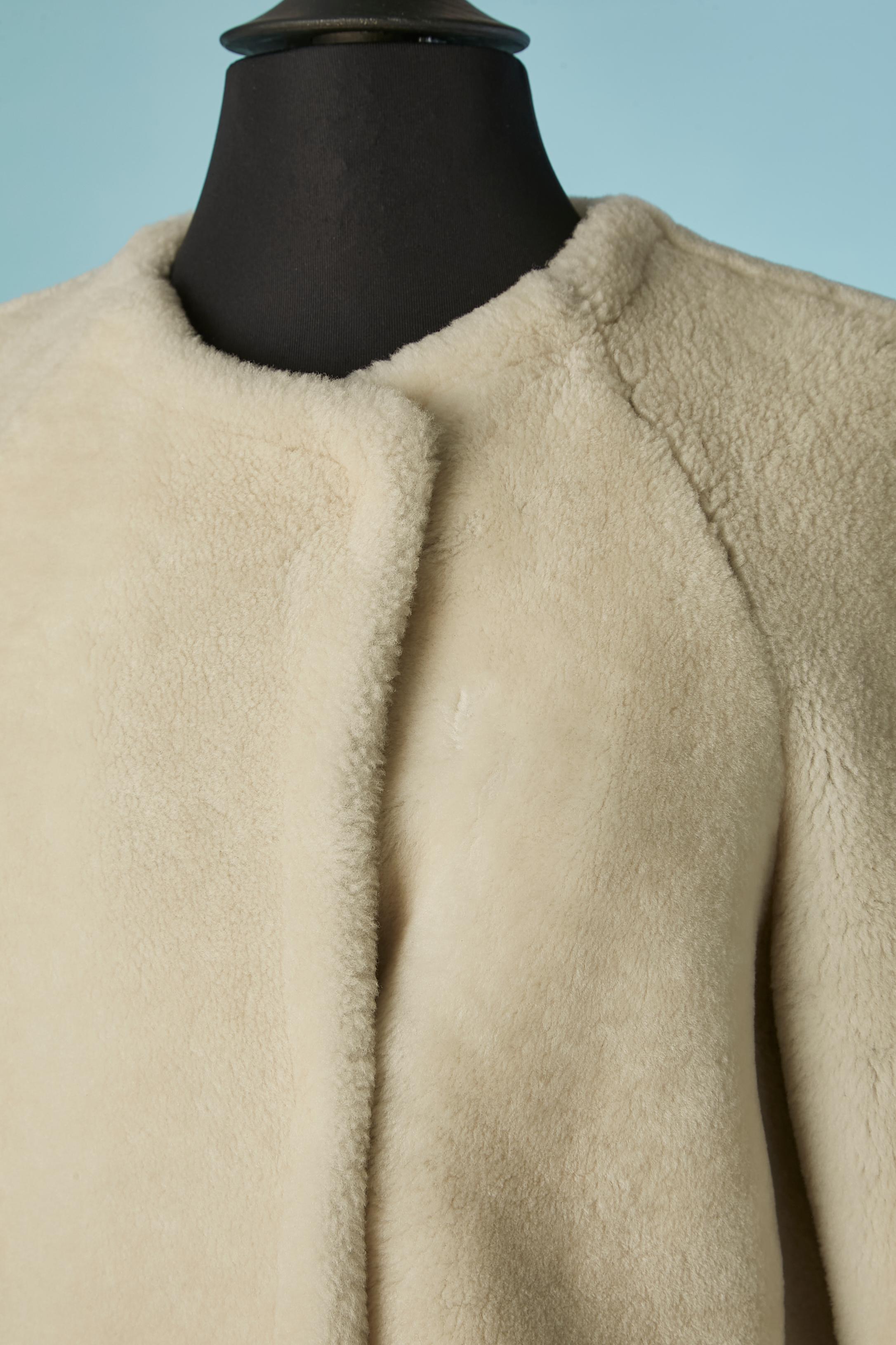 Cappotto in shearling bianco sporco. Non c'è l'etichetta della composizione del tessuto per la fodera, ma probabilmente è in rayon. Manica raglan. Chiusura con gancio e occhiello al centro della parte anteriore. Tasca su entrambi i lati. 
TAGLIA M