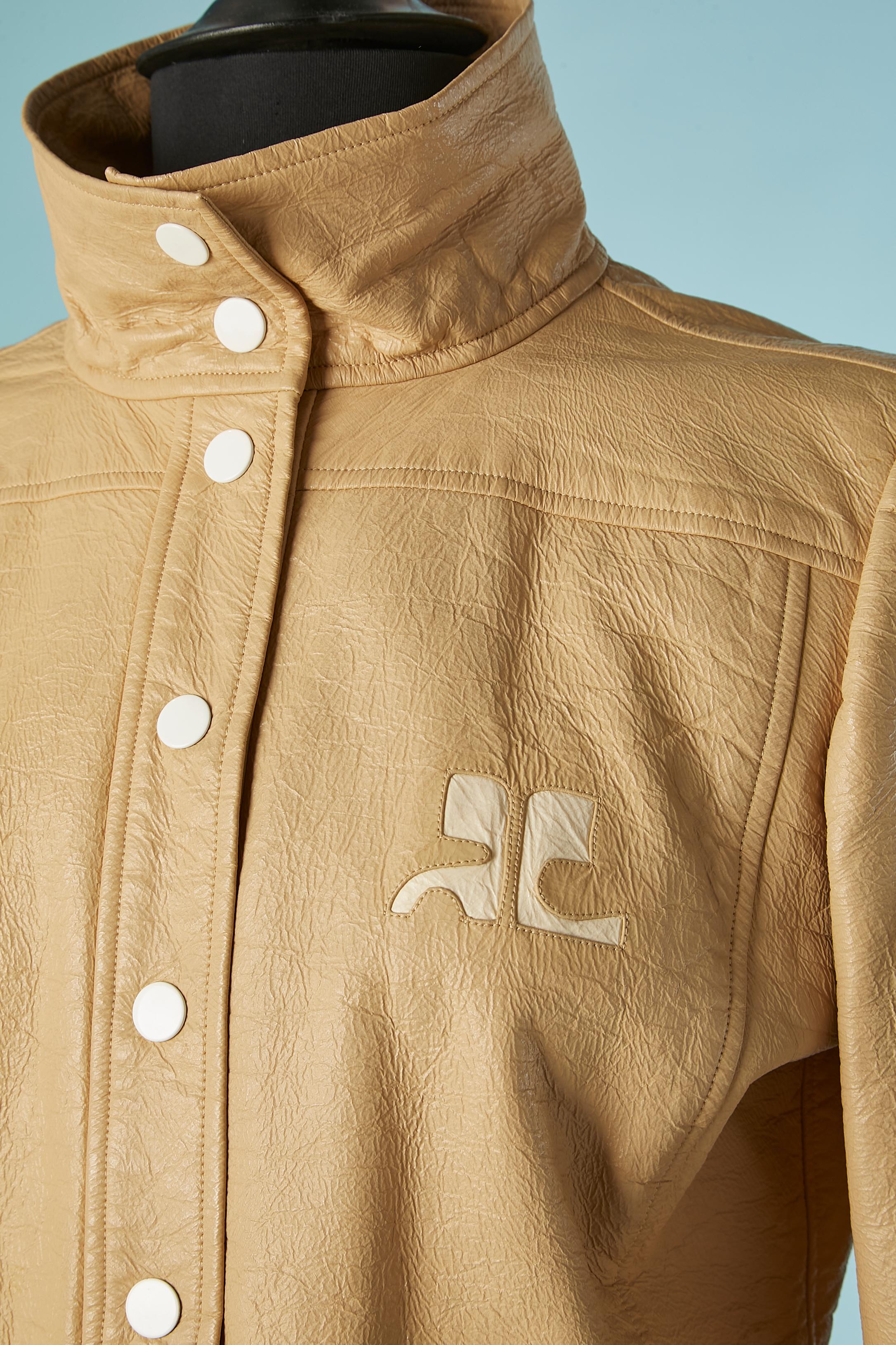 Veste en vinyle beige à simple boutonnage avec fermeture à boutons-pression blancs sur le milieu du devant et sur les poignets. 
Composition du tissu principal : 85% coton, 15% polyuréthane. Doublure détachable (avec bouton-pression) de la marque :