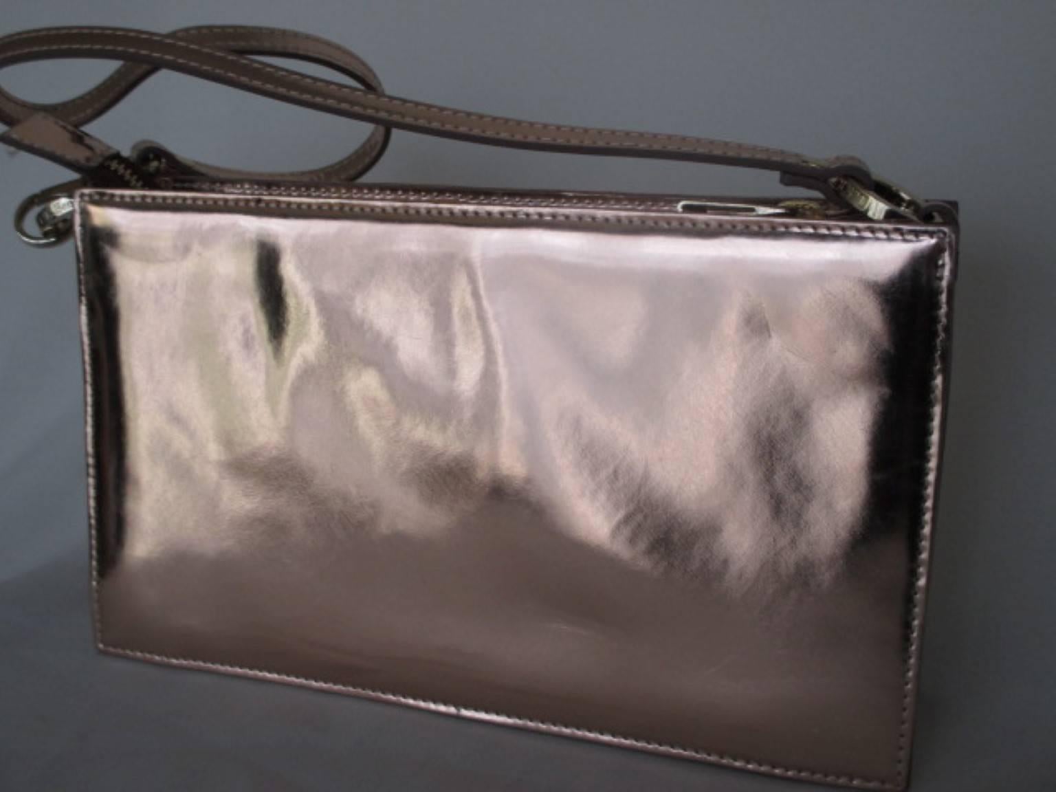 Le sac Posy de LK Bennett est un sac métallique or rose en cuir fini miroir. Il peut être porté comme une pochette ou suspendu à l'épaule, au coude ou au poignet
Ce sac  possède une fermeture éclair intérieure, une bandoulière et une légère usure