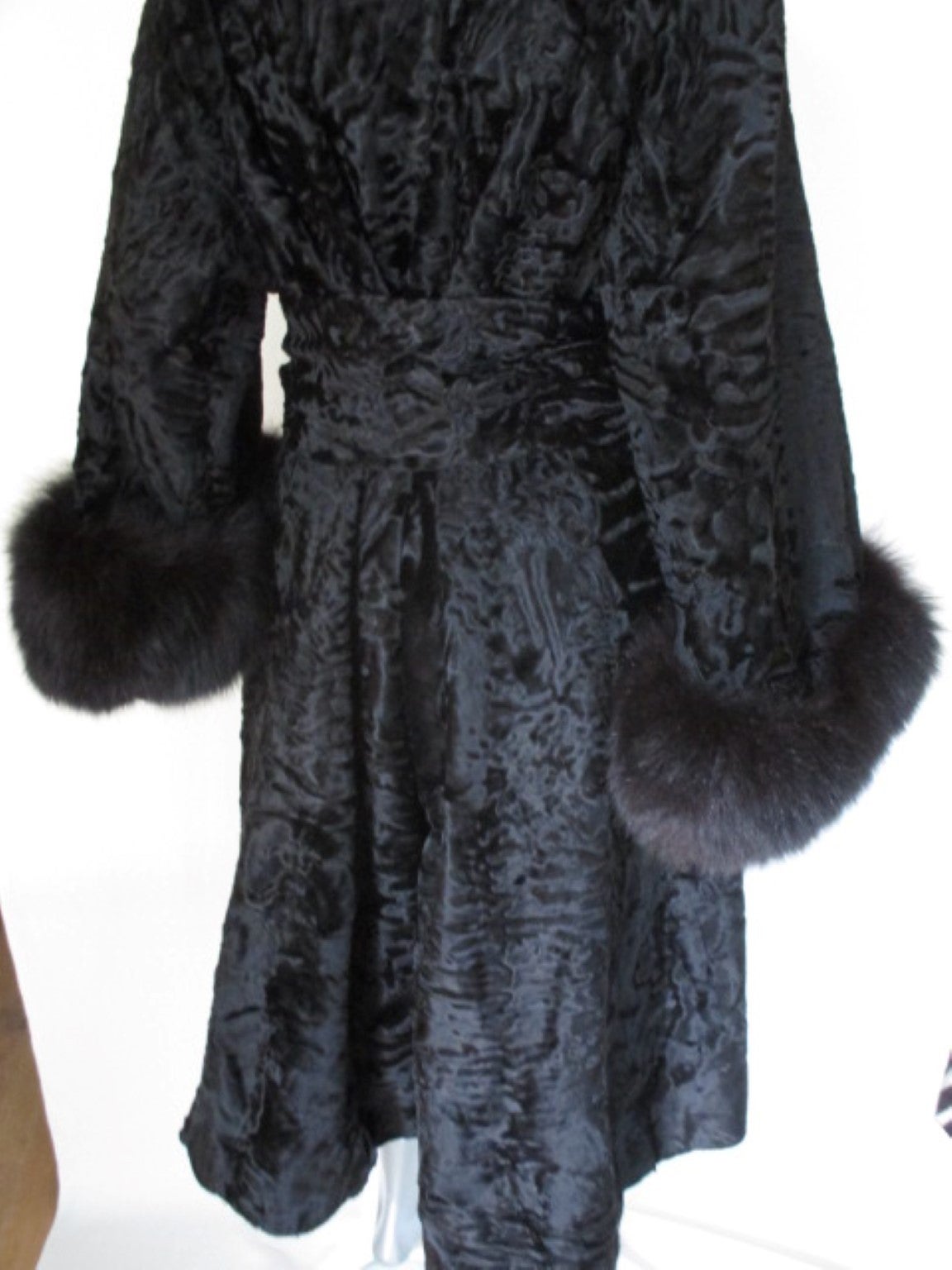 This vintage black Persian Lamb/Astrakhan coat has black fox cuffs and comes with a belt made from the same Astrakhan and fox,
The coat has 5 hooks , 4 buttons, 1 closing hook at the collar and an inside pocket.
The coat is a belted A-line model
