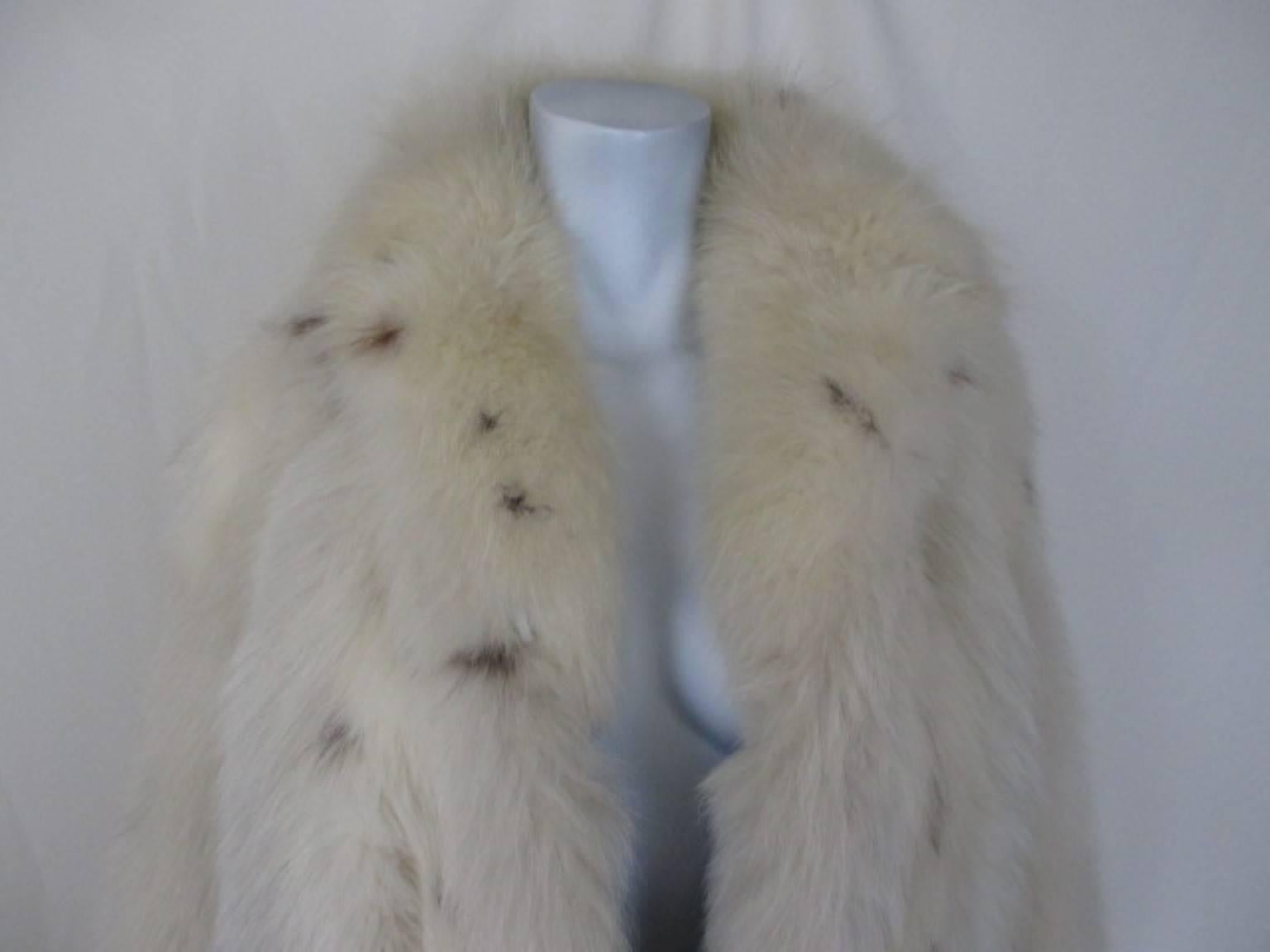 This coat has long fluffy soft hair, is snow white with black spots, has 2 pockets, 1 inside pocket and 3 closing hooks.
The sleeves are at the end designed with the feets of the animal ( which you can remove) and the sleeves are made narrow