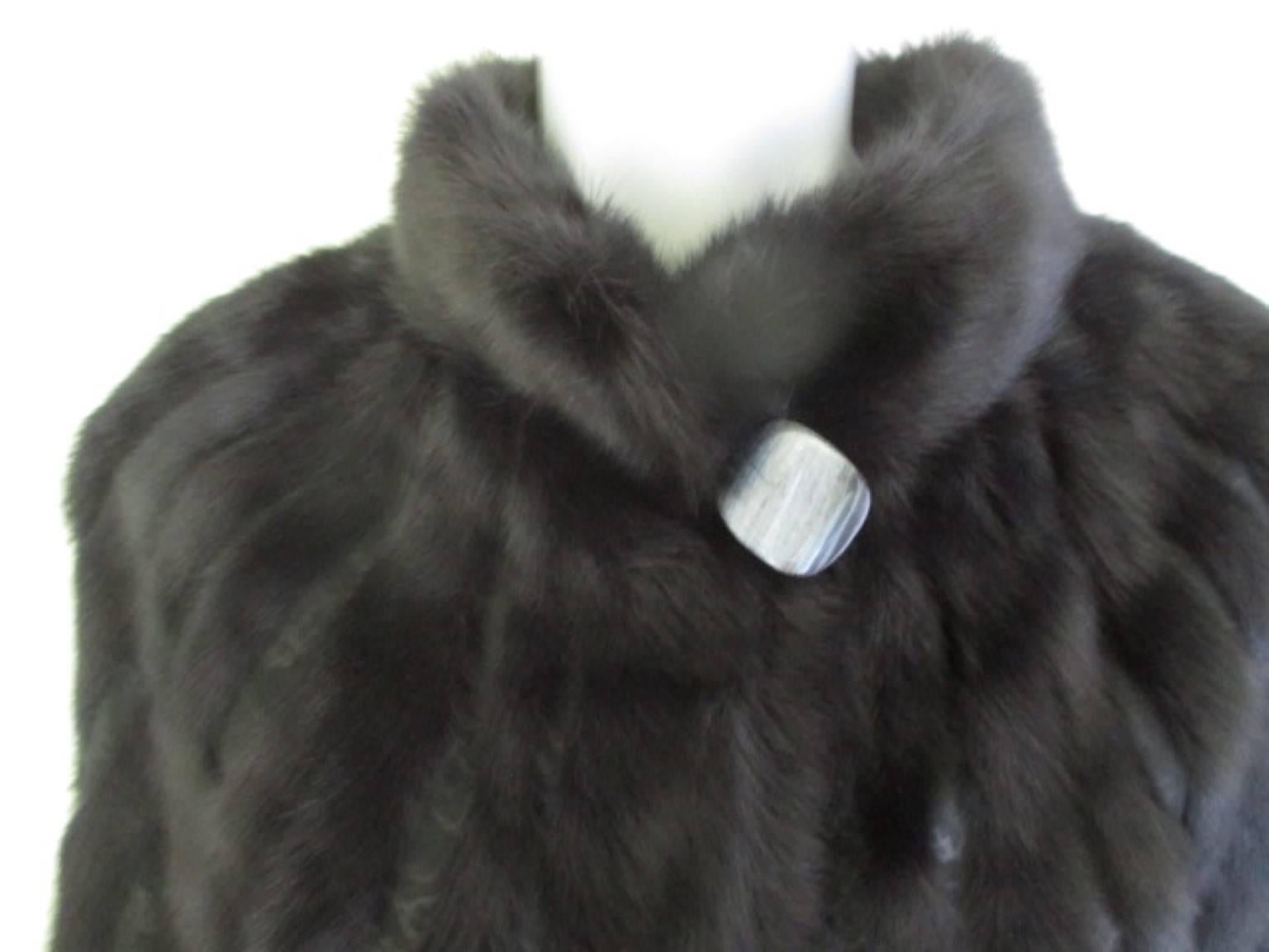 This coat is made of superb quality black Saga soft mink fur/soft suede leather and is very light to wear.
The sleeves are wide (batwing style)
It has 2 pockets, 3 closing hooks and 2 buttons, one t the collar and one at the bottom.
Its in excellent