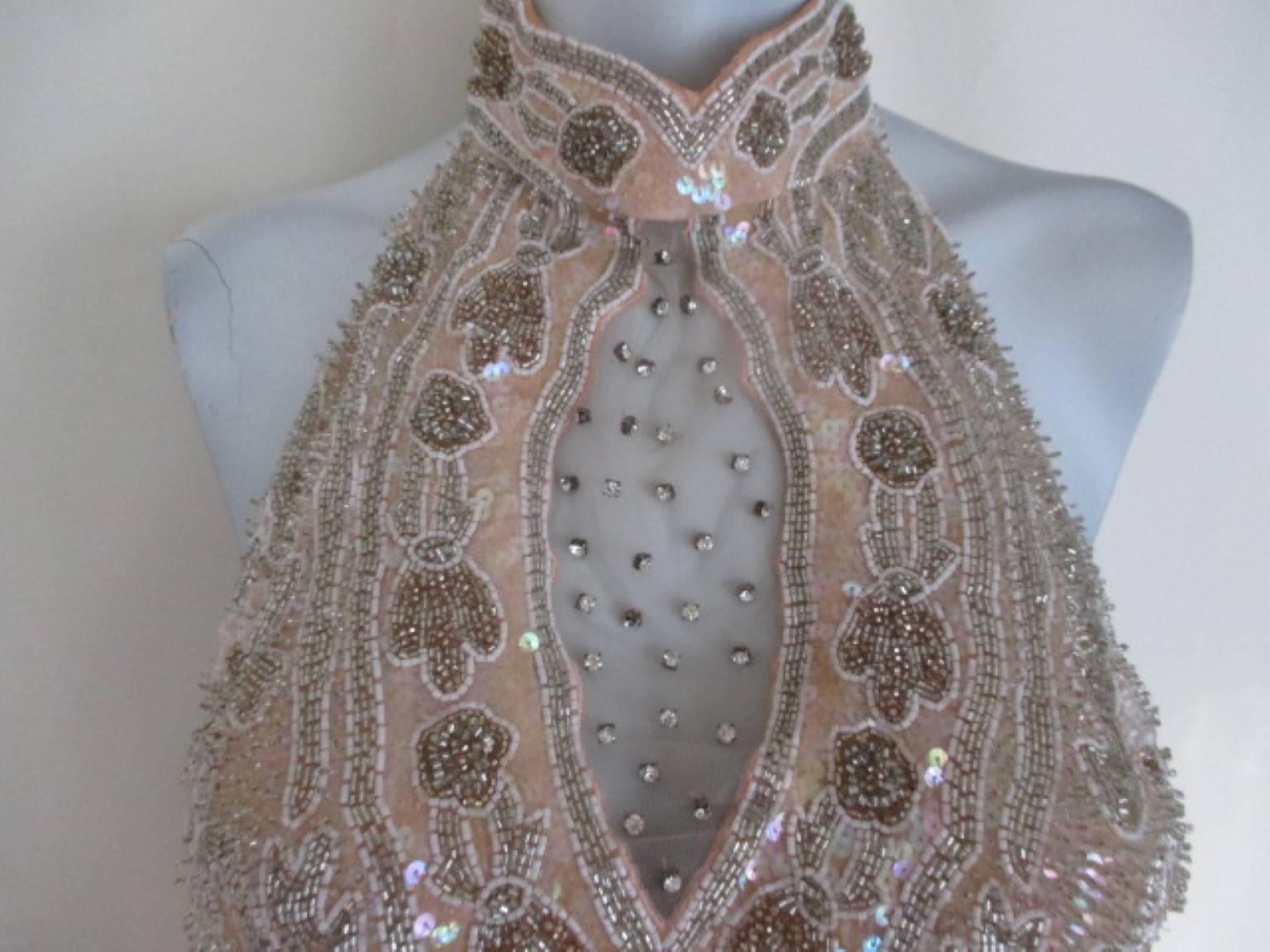 This is a Vintage mid 80’s BLACK TIE by Oleg Cassini peach color evening dress. 
 Oleg Cassini was the former designer of Jackie Kennedy.
The exquisite shapely lines are heavily beaded in sequins, and bugle beads in  on fully lined Silk. 
The dress