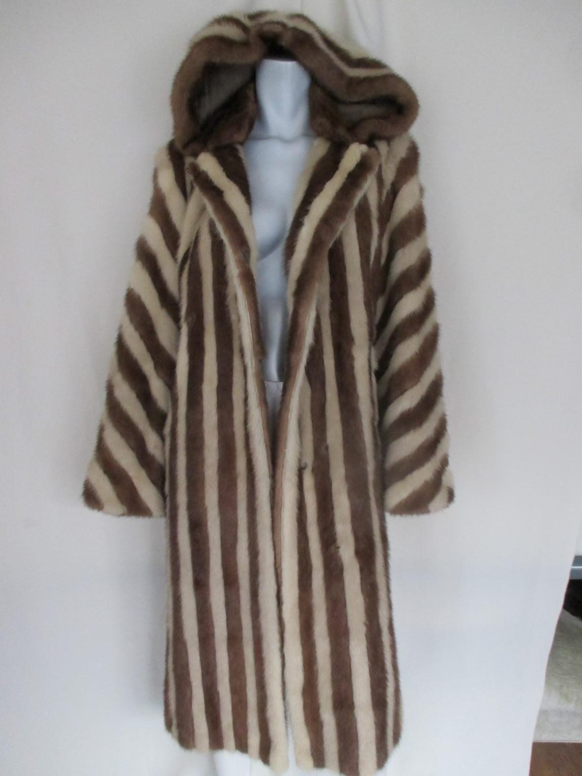 This brown/creme mink coat with a large hood , has side splits, 1 hook at the collar, 3 closing hooks and 2 pockets.
The end of the sleeves can be fold from the total lenght 62 cm to 57 cm
It's in good vintage condition with some minimal wear of