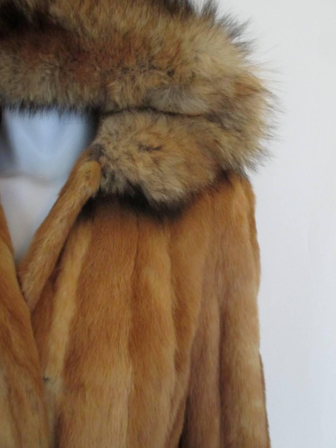 This fur coat has a hood with fox fur ruff, with  2 pockets, 3 hooks and 1 button at the collar.
The wrists are lined with leather.
The coat is in fair condition, shows stain and snags at the lining.
Size is about EU 38/US 8