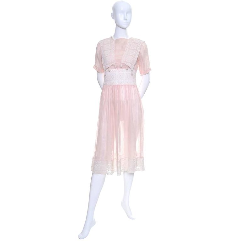 This pretty vintage dress is made in a semi sheer pink cotton voile with tone on tone stripes and beautiful crochet lace.  The dress snaps closed in several places and the pretty bodice has crochet dangles off of the lace panels. The beautiful