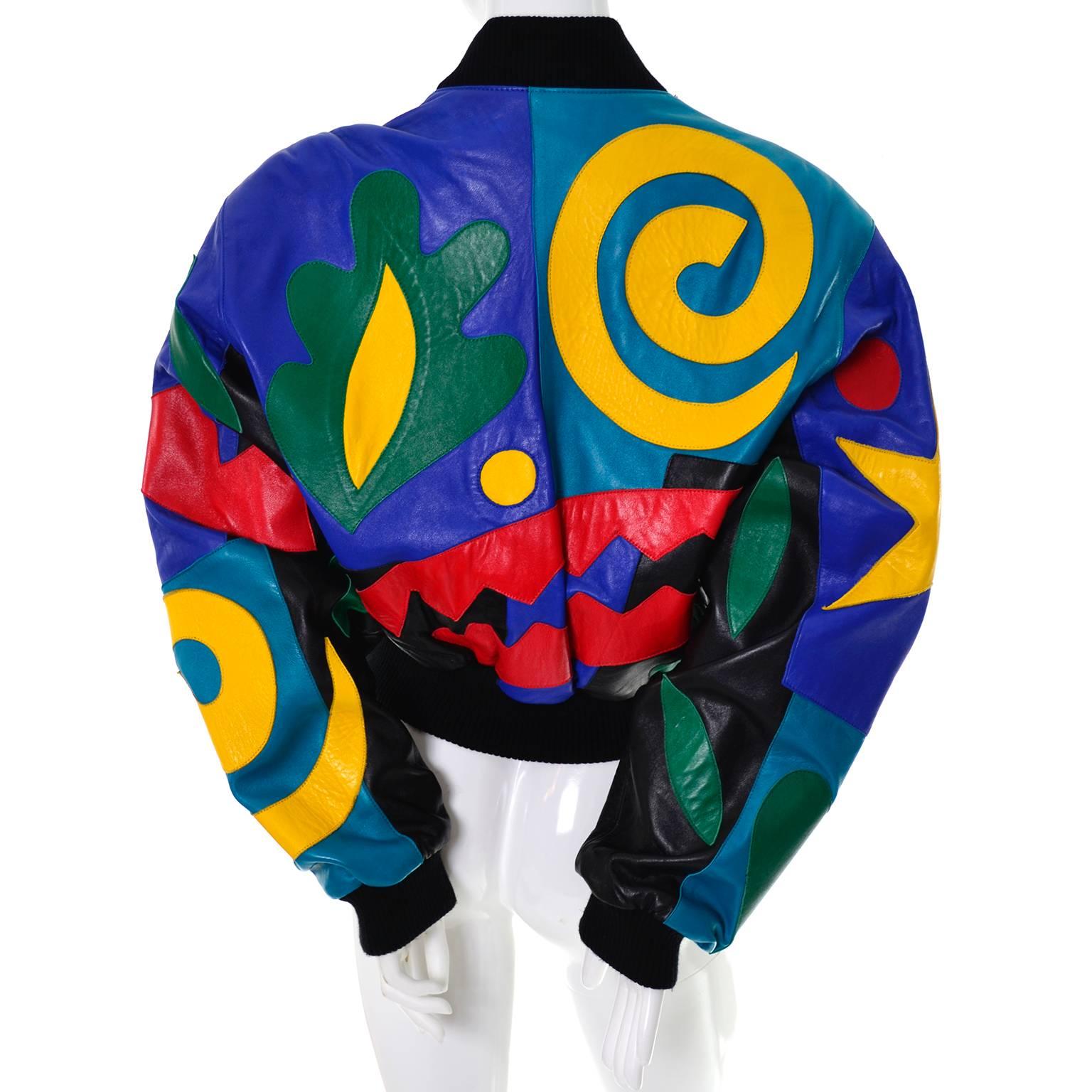 This sensational vintage leather bomber jacket was designed by Michael Hoban for North beach Leather.  There are bright shapes including stars, swirls, and leaves in shades of yellow, green, red and black.  The jacket zips up the front and has black