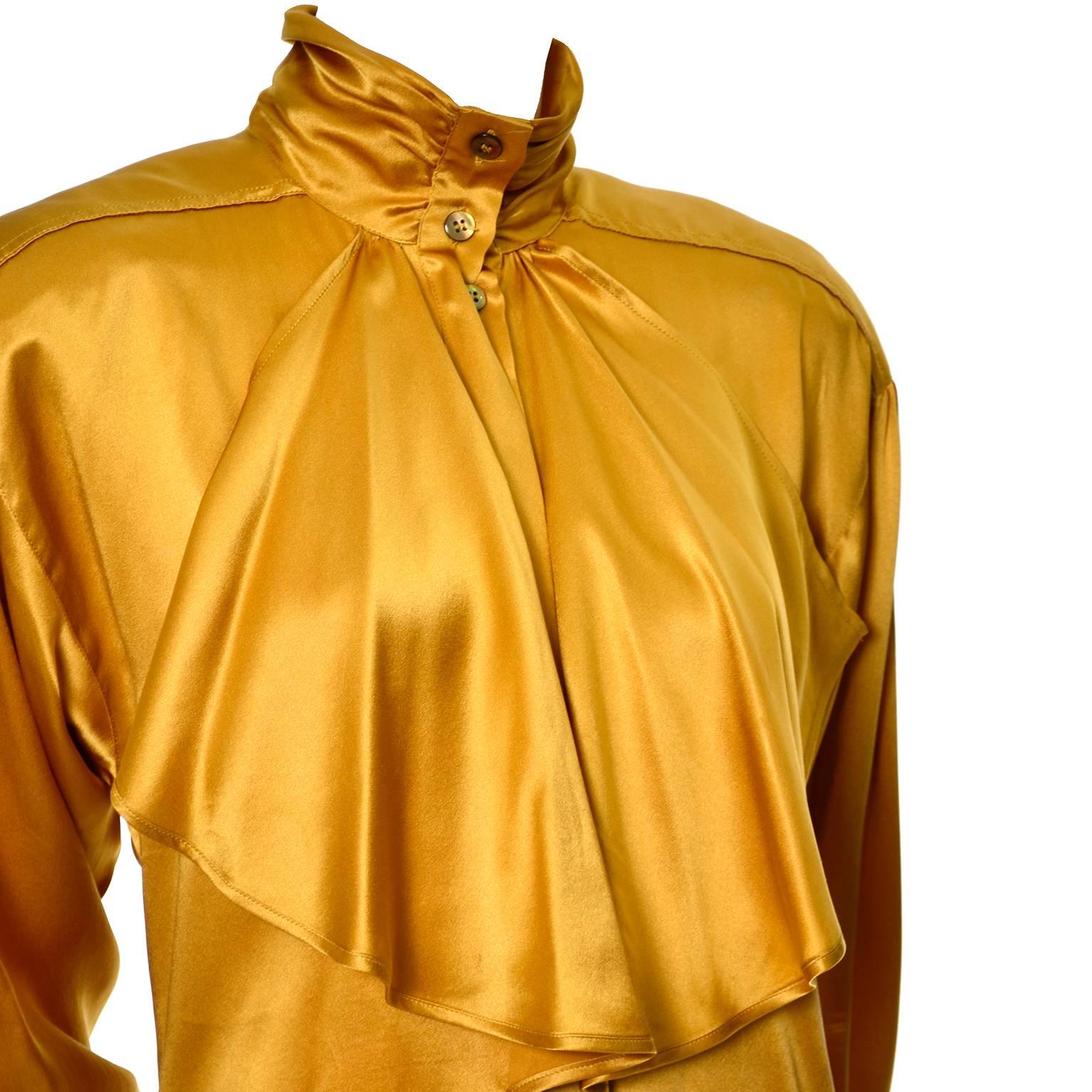 This luxurious gold silk blouse from Escada is from the 1980’s and is labeled a European size 36.  The blouse has beautiful gathered bishop sleeves that drape a little off from the shoulders with slight shoulder pads, and a pleated high button