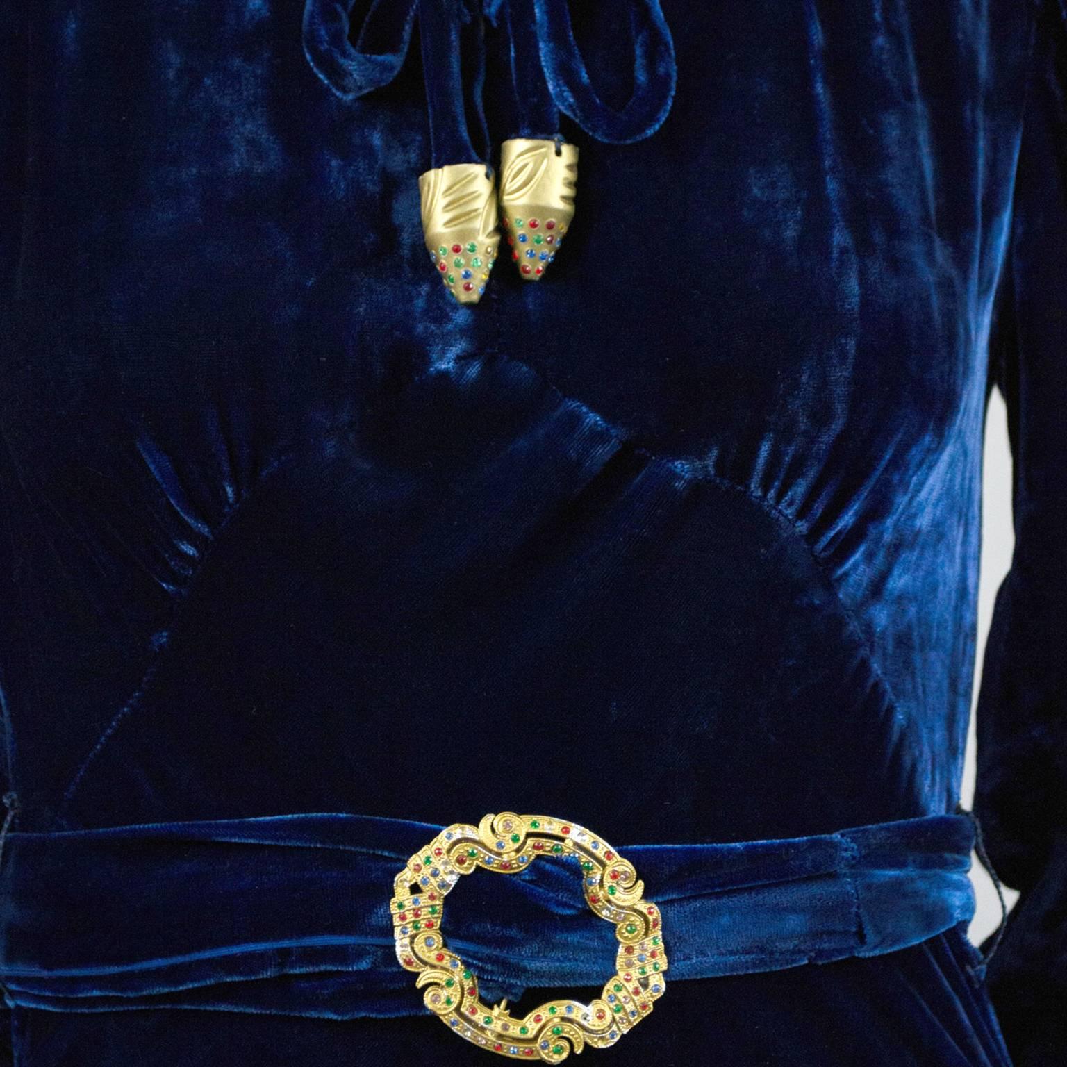 This is a gorgeous blue rayon velvet vintage dress from the 1930's.  The dress has beautiful ties at the neck that have gold metal aglets with multi covered rhinestones. The belt is made in the same luxe blue velvet and the gold buckle has the same