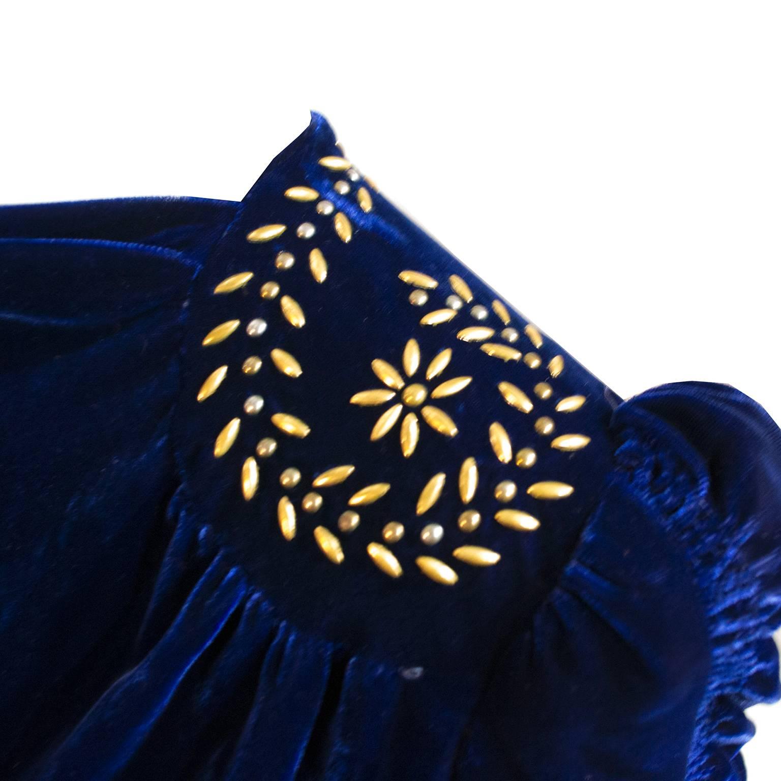 This late 1930's vintage dress is made of a luxurious blue velvet and has decorative metal on the shoulders that look like flower petals or leaves. The ruching on the sleeves makes a beautiful statement and there is a side zipper and covered buttons