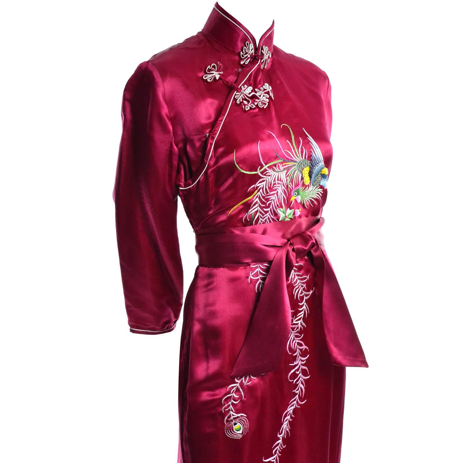 This is a stunning vintage Chinese Cheongsam dress in a rich raspberry red silk with multi colored fine embroidery.  The abstract peacock bird motif flows down the front of the dress and the dress closes with snaps and frog closures.  There is a