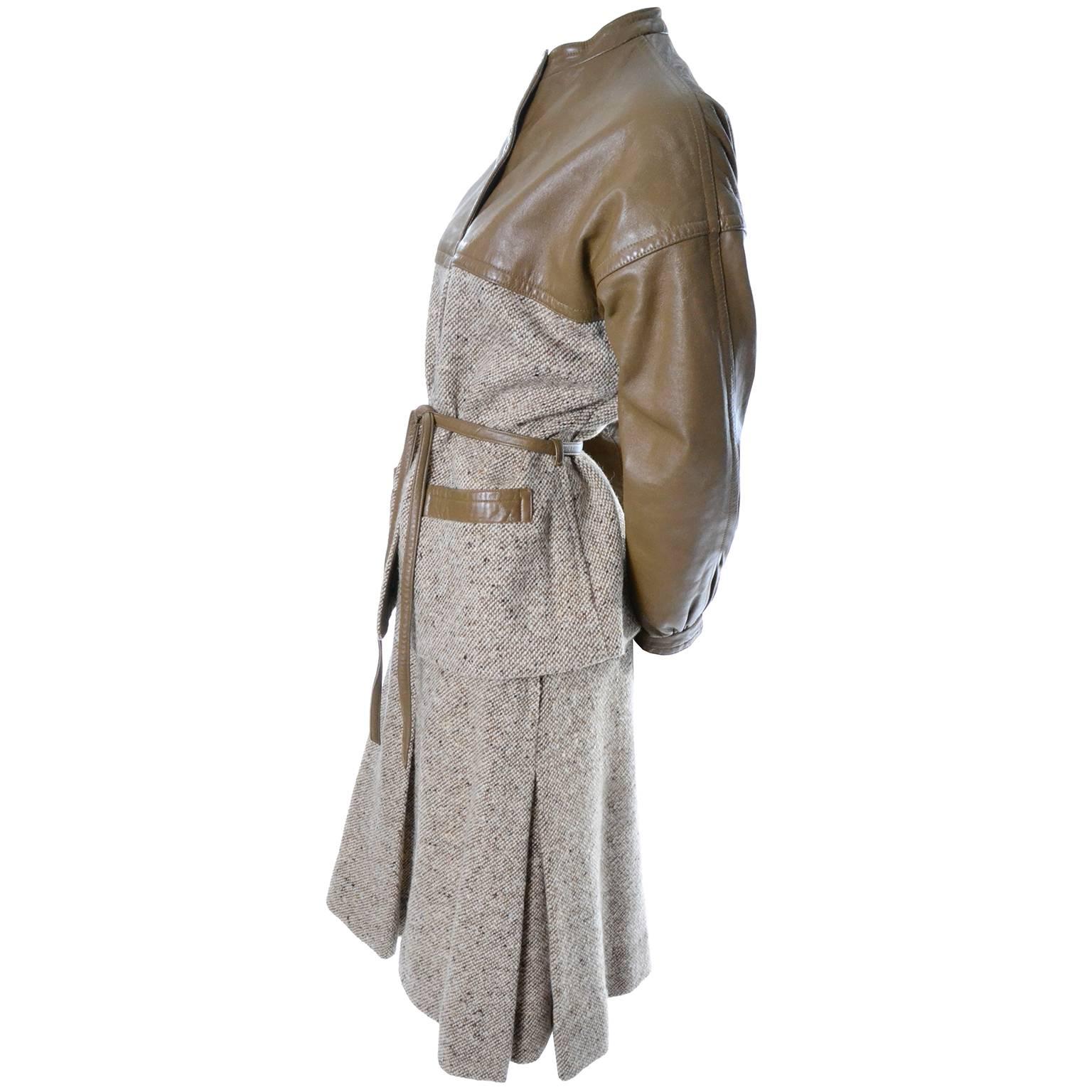 This Bonnie Cashin skirt suit is made of a tan brown tweed and is trimmed in tan leather.  The skirt has single pleat on each side and in front and back, leather trim at the waist band,and a side zipper.  The jacket snaps closed and has leather