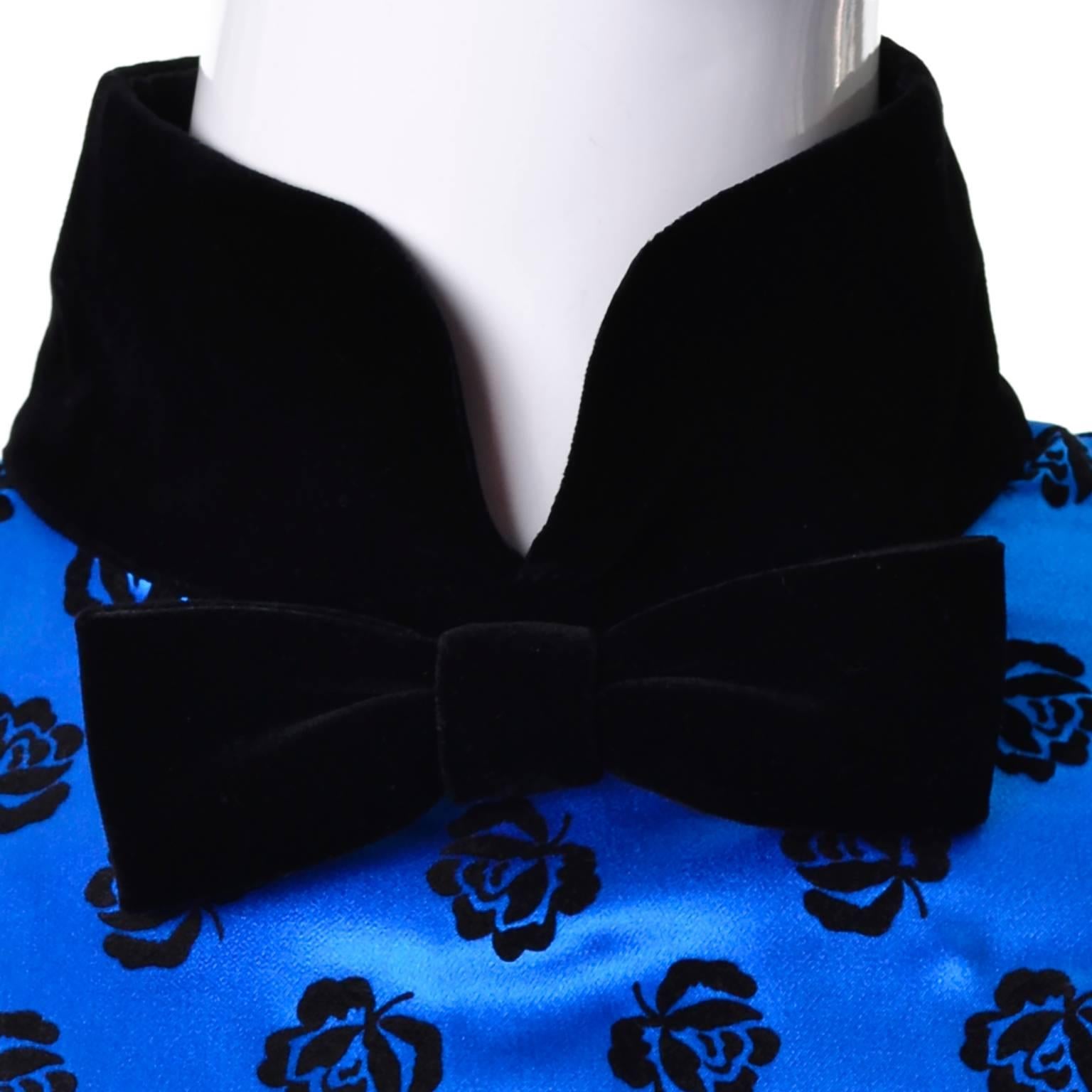 This is a beautiful 100% silk vintage Escada blouse designed by Margaretha Ley in the 1980's. The neck and bow at the neck are black velvet, as are the cuffs and decorative flocked roses covering the shimmering blue silk blouse.  This blouse is