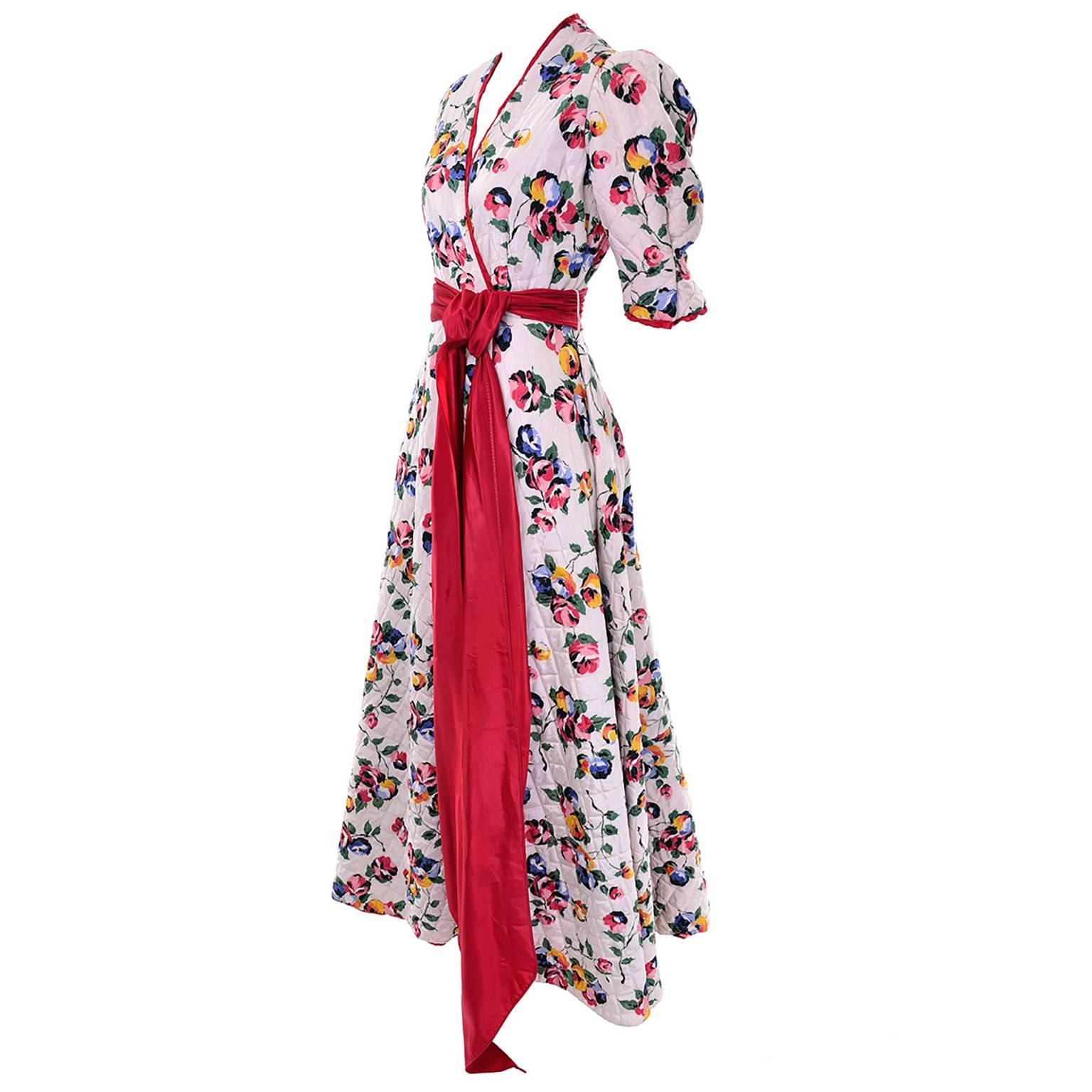 Ce manteau d'intérieur vintage matelassé à fleurs, rose pâle, des années 1940 est superbe en personne. Cette magnifique robe est doublée de rouge, bordée de rouge et munie d'une magnifique ceinture rouge.  Il s'agit d'une taille Small et il est en