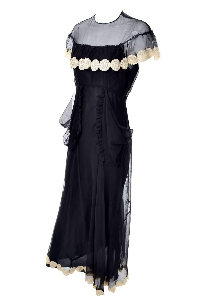 This very unique art deco era 1930's vintage dress has an illusion bodice and circle lace appliques along the hem and below the overlay on the bust. This incredible dress is long, with two sheer hip pockets made of organza that ruffle along the